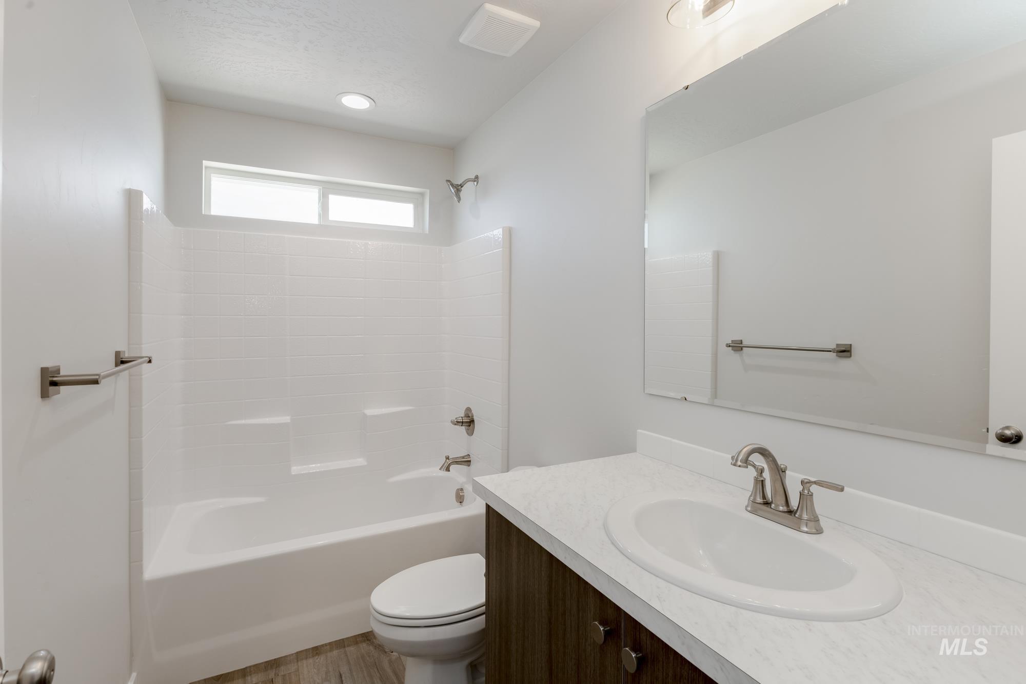 Full bath with vanity, shower / tub combination, and wood finished floors