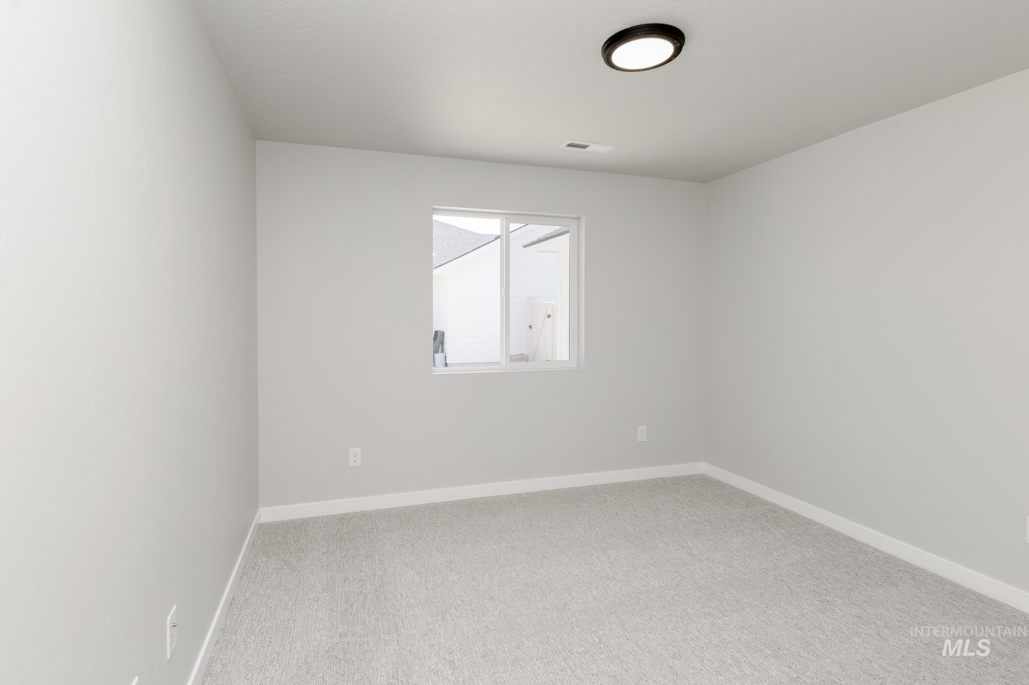 Carpeted spare room featuring baseboards