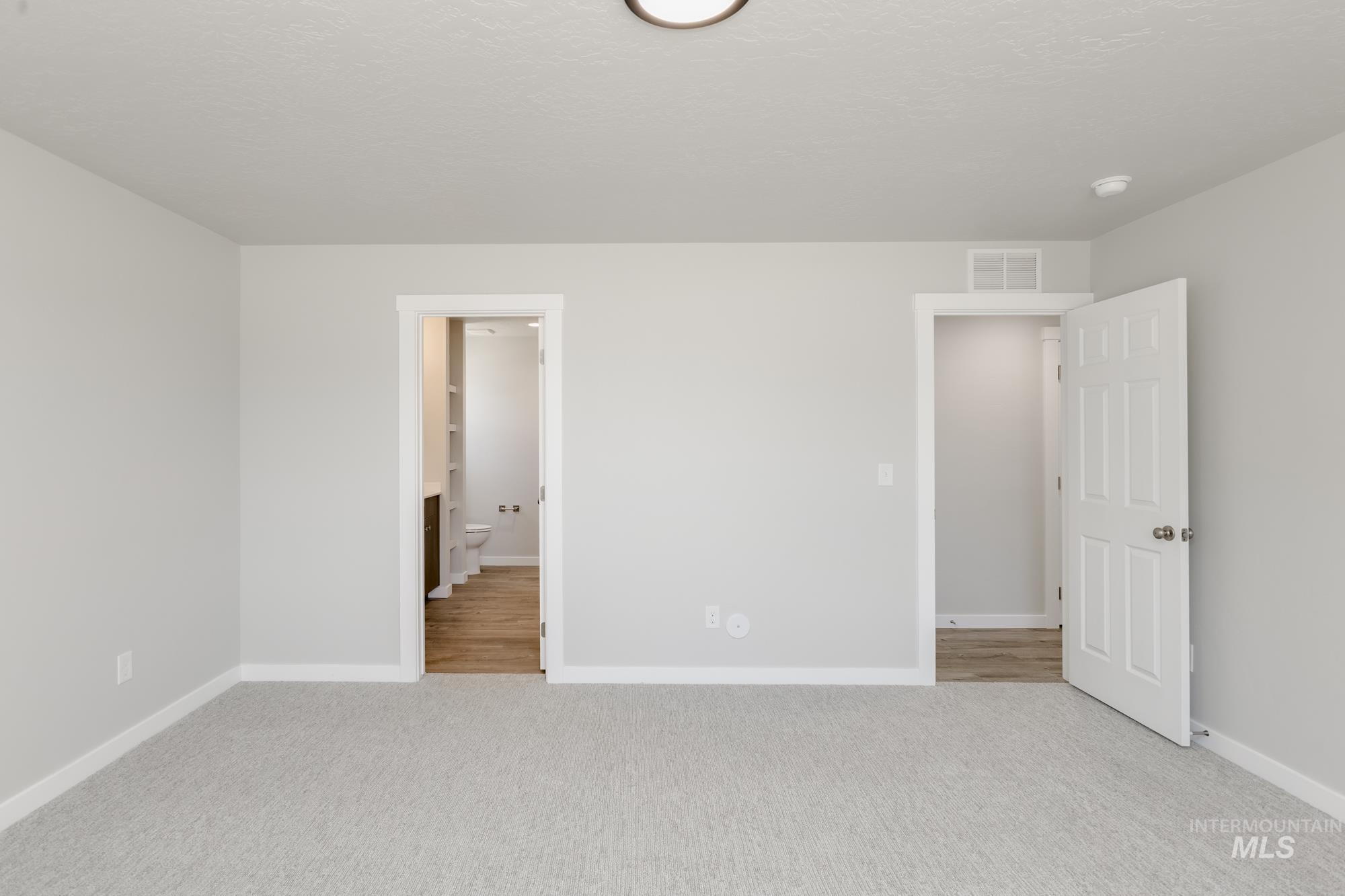Unfurnished bedroom with light carpet and connected bathroom