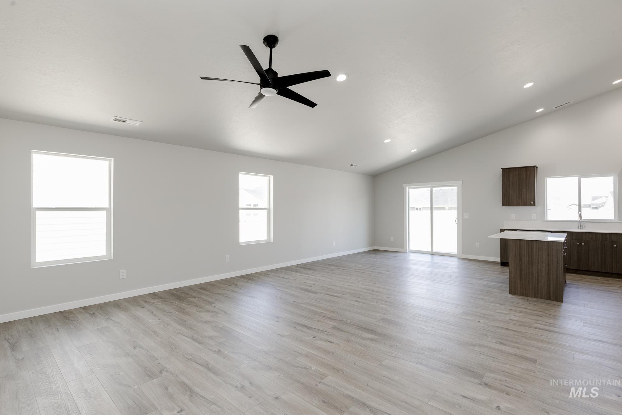 Unfurnished living room with lofted ceiling, a ceiling fan, light wood-style floors, and recessed lighting