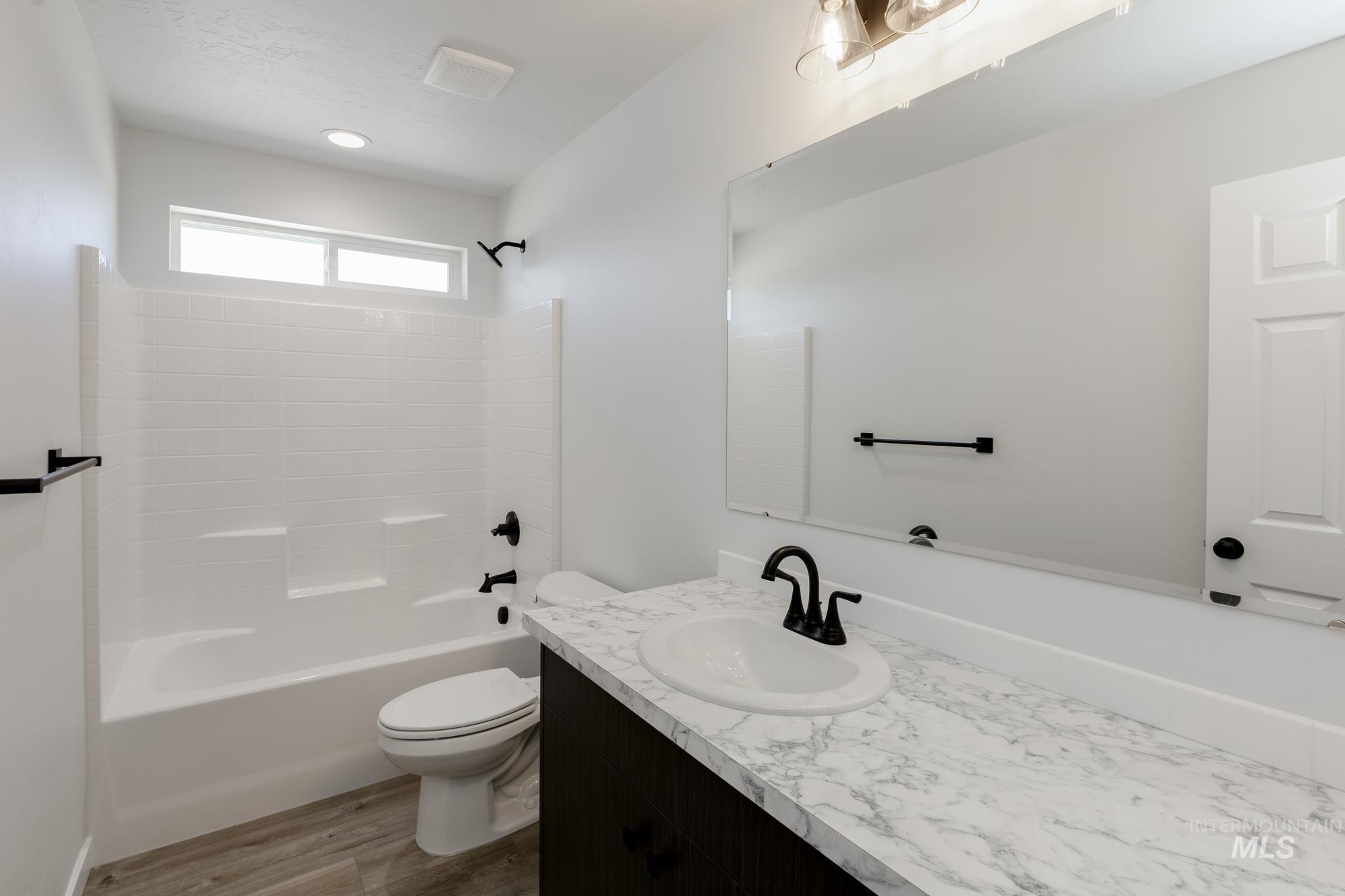 Bathroom featuring vanity, bathtub / shower combination, and wood finished floors