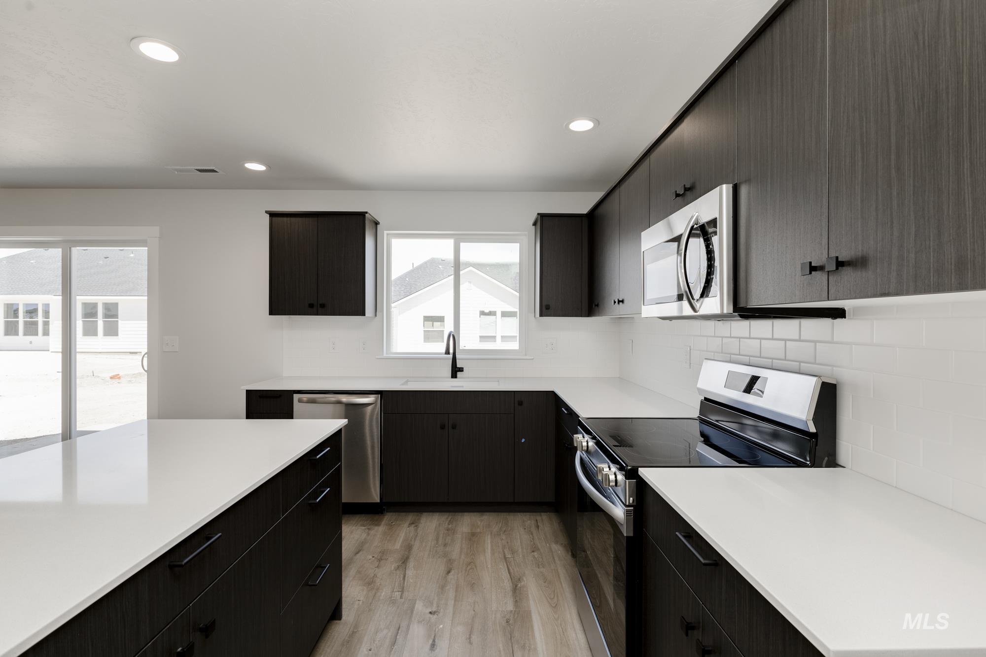Kitchen featuring appliances with stainless steel finishes, backsplash, light wood-type flooring, light countertops, and recessed lighting