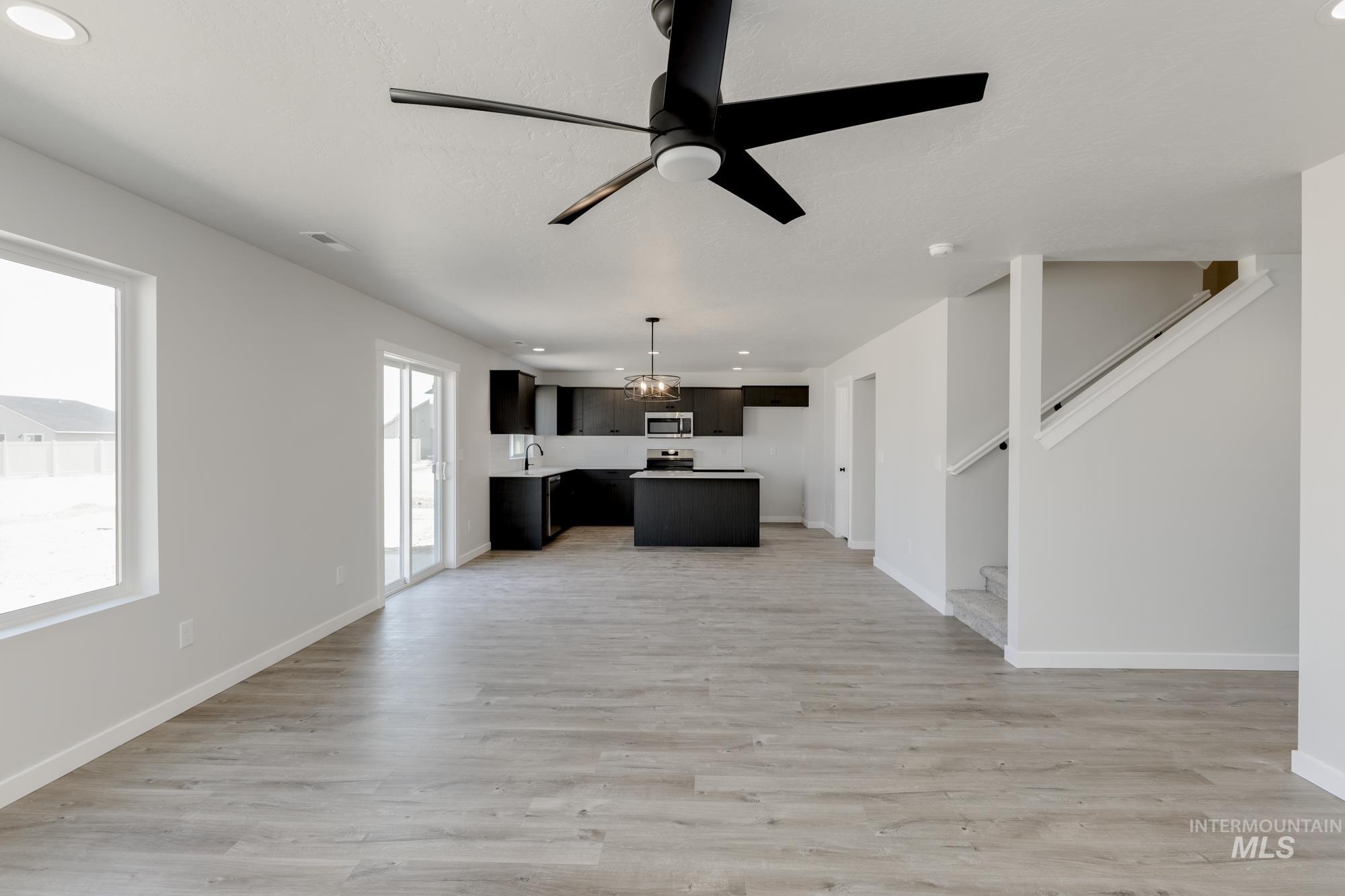 Unfurnished living room with a ceiling fan, light wood-type flooring, stairway, and recessed lighting