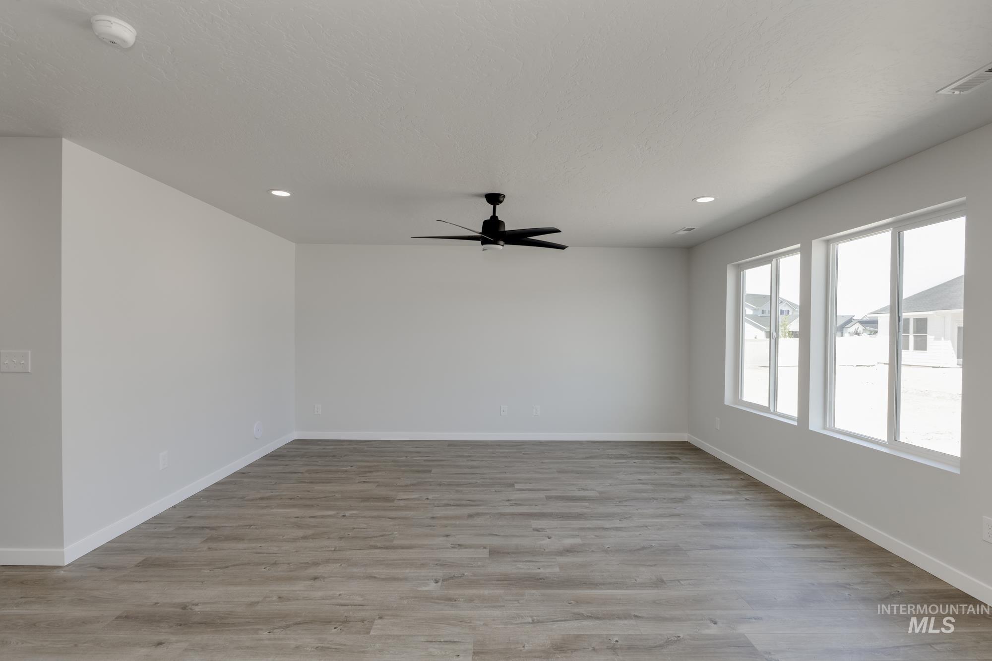 Empty room featuring a ceiling fan, recessed lighting, light wood-style flooring, and a smoke detector