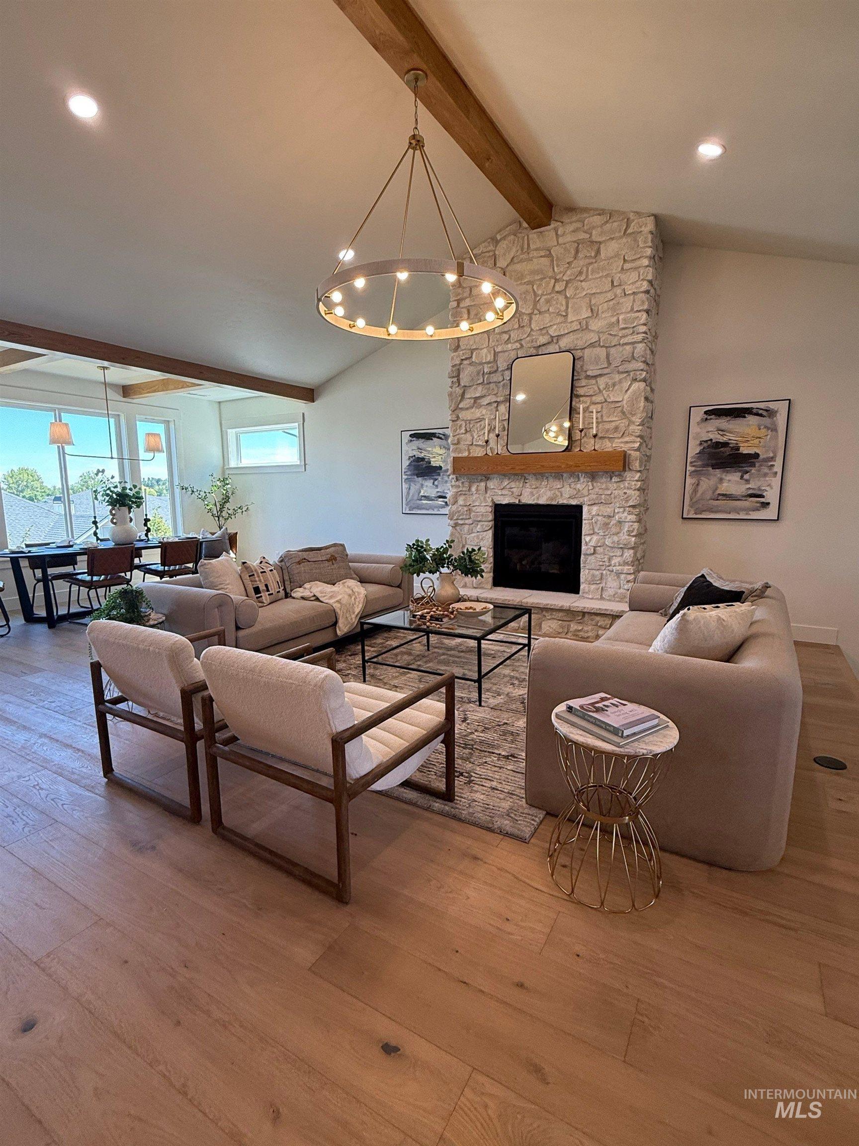 Living area featuring light wood-type flooring, a stone fireplace, a chandelier, and recessed lighting