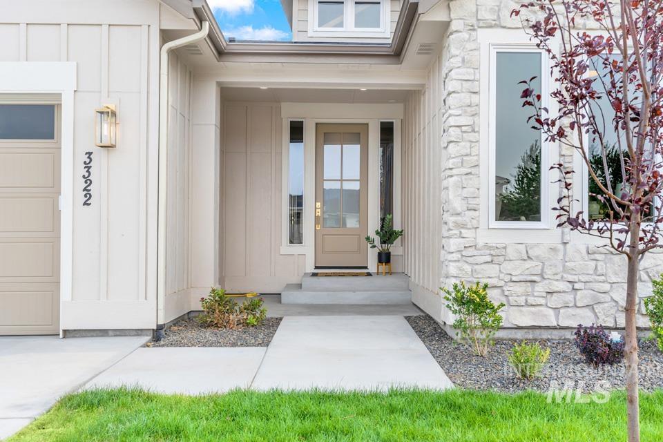 Entrance to property with stone siding, board and batten siding, and a garage