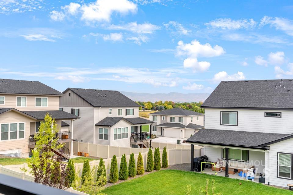 Rear view of property featuring a patio, a residential view, roof with shingles, and a fenced backyard