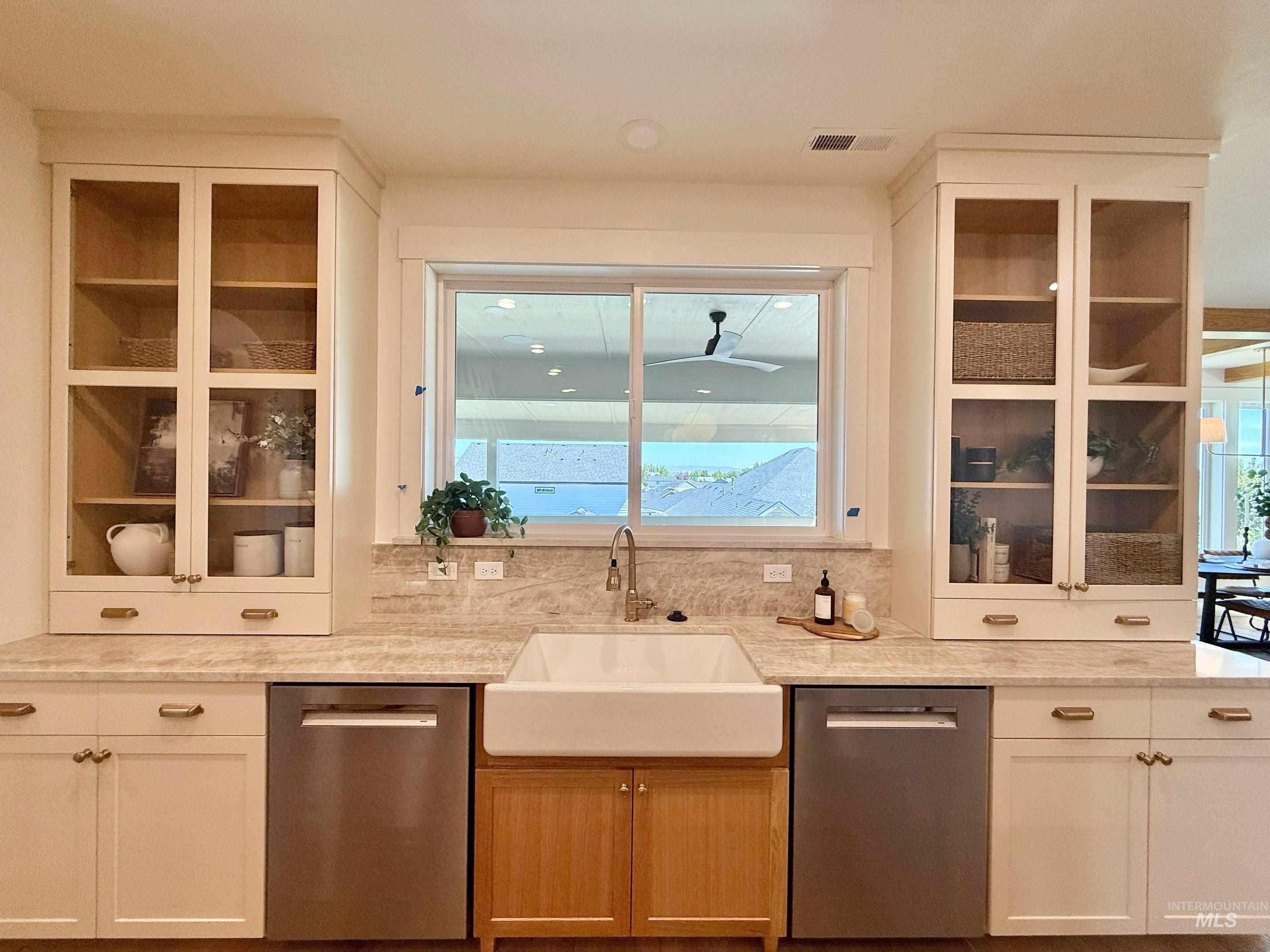 Kitchen with glass insert cabinets, dishwasher, and light stone counters