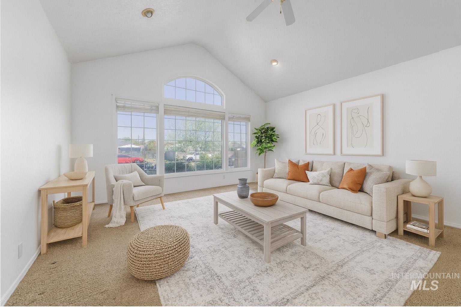 Carpeted living area featuring ceiling fan and high vaulted ceiling