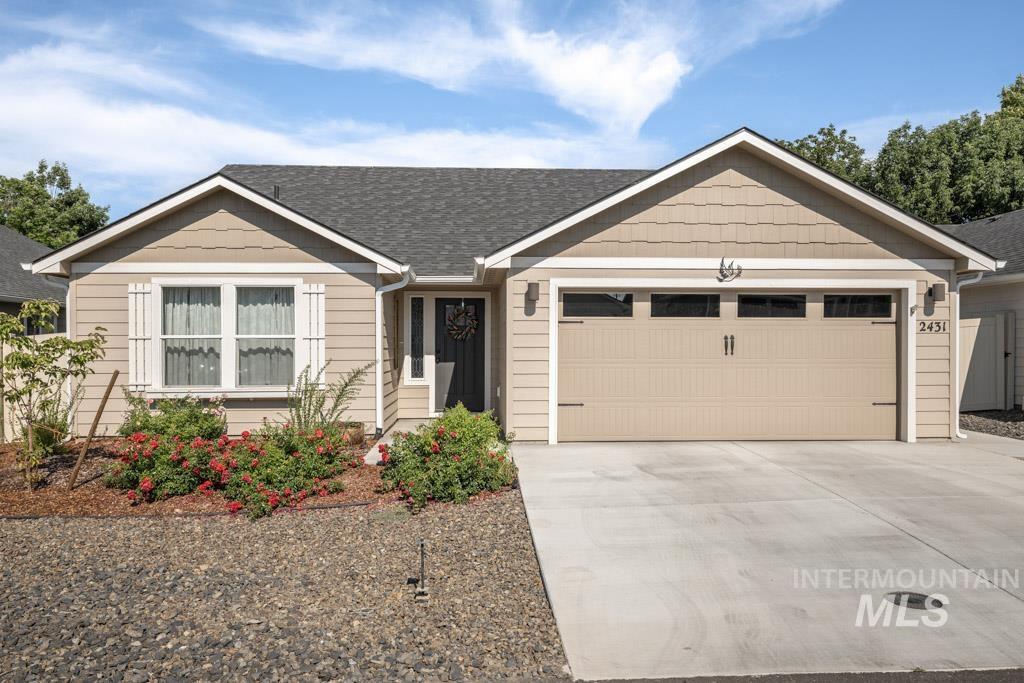 View of front facade featuring an attached garage, driveway, and a shingled roof