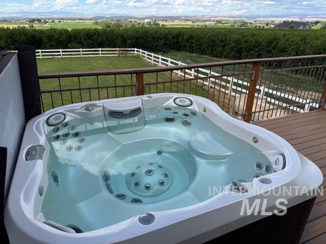 Wooden terrace featuring a hot tub, a view of countryside, and a yard