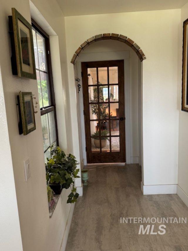 Doorway to outside with arched walkways and wood finished floors