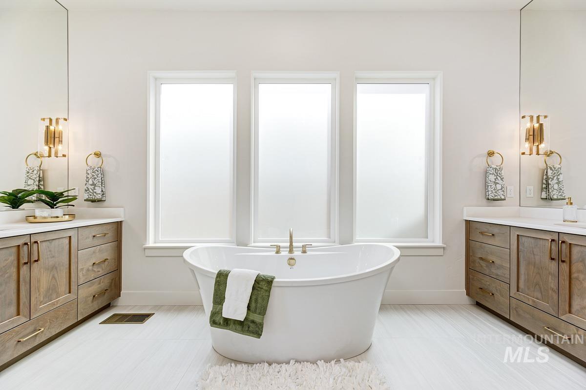 Full bath featuring vanity, a soaking tub, and plenty of natural light