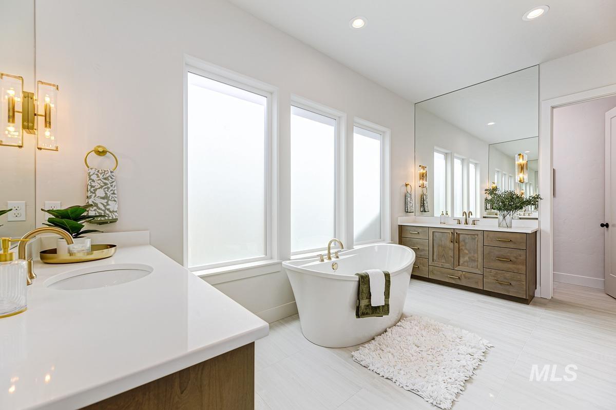 Full bath with a soaking tub, two vanities, and recessed lighting