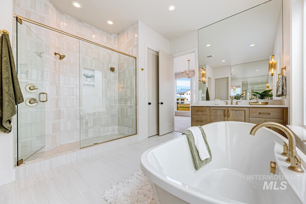 Full bath with a soaking tub, a stall shower, recessed lighting, vanity, and a chandelier