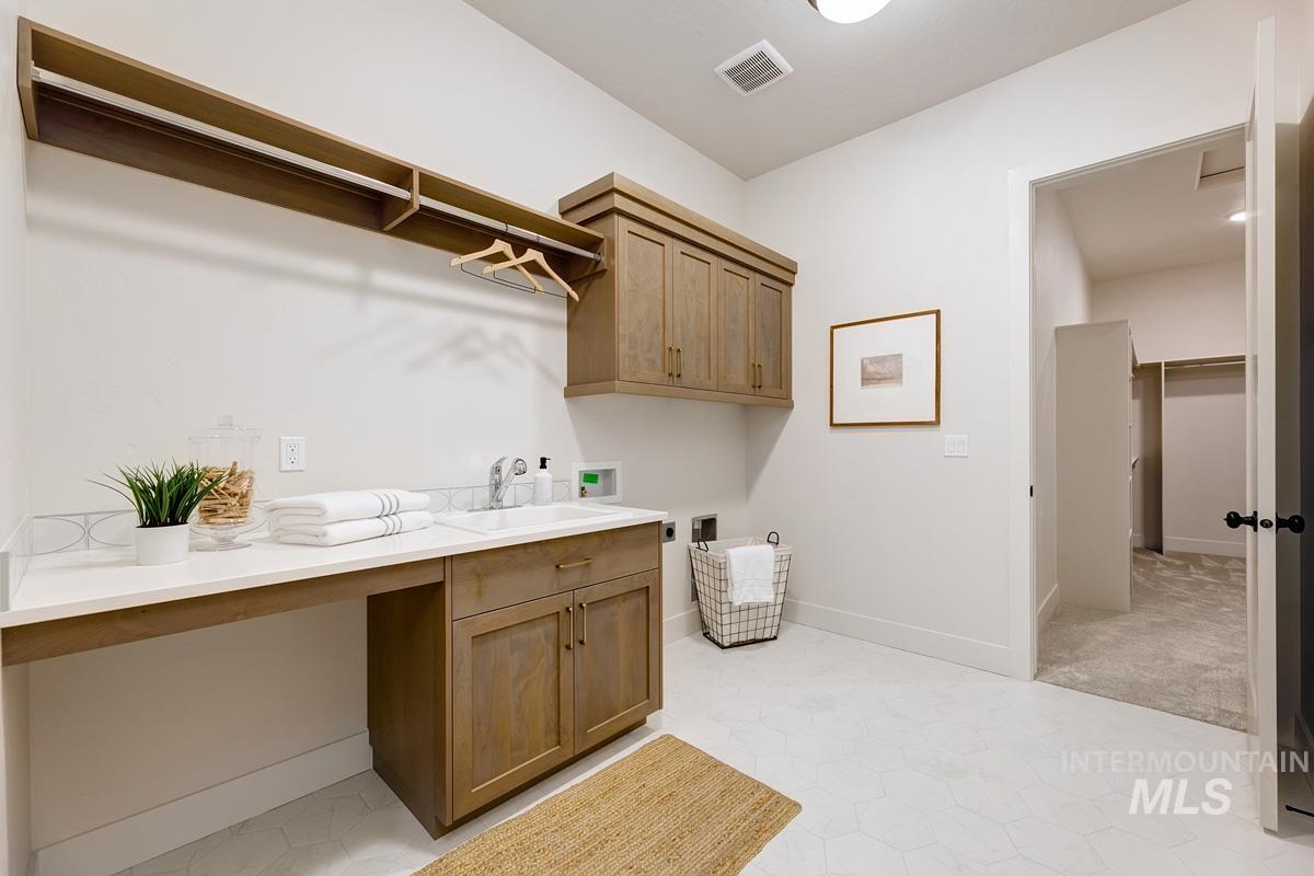 Washroom featuring washer hookup, cabinet space, and light tile patterned floors