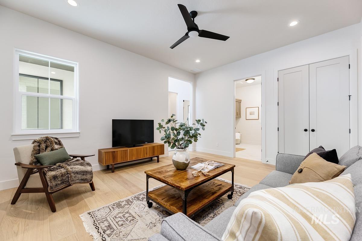 Living room featuring light wood-style floors, a ceiling fan, and recessed lighting