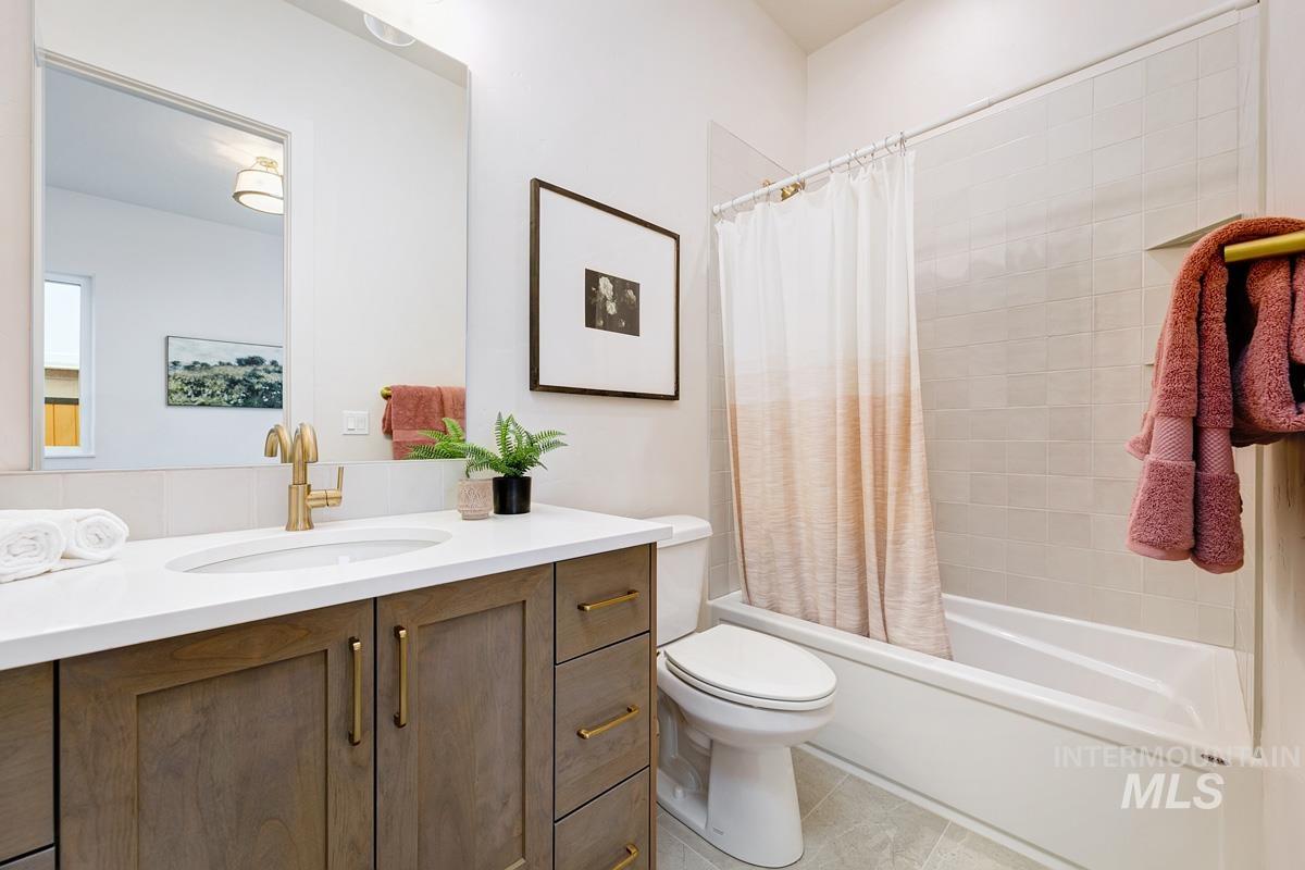 Bathroom featuring shower / tub combo, vanity, and light tile patterned flooring