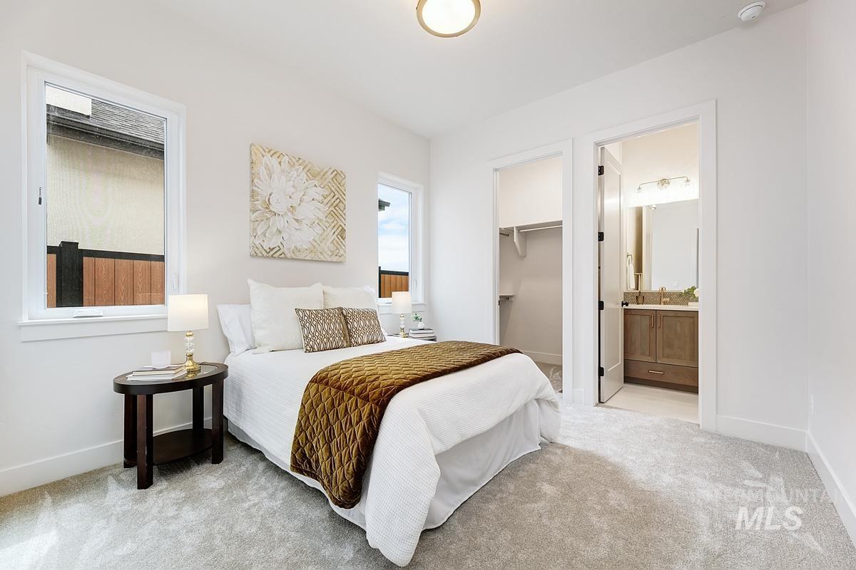 Bedroom featuring light colored carpet, a spacious closet, and connected bathroom