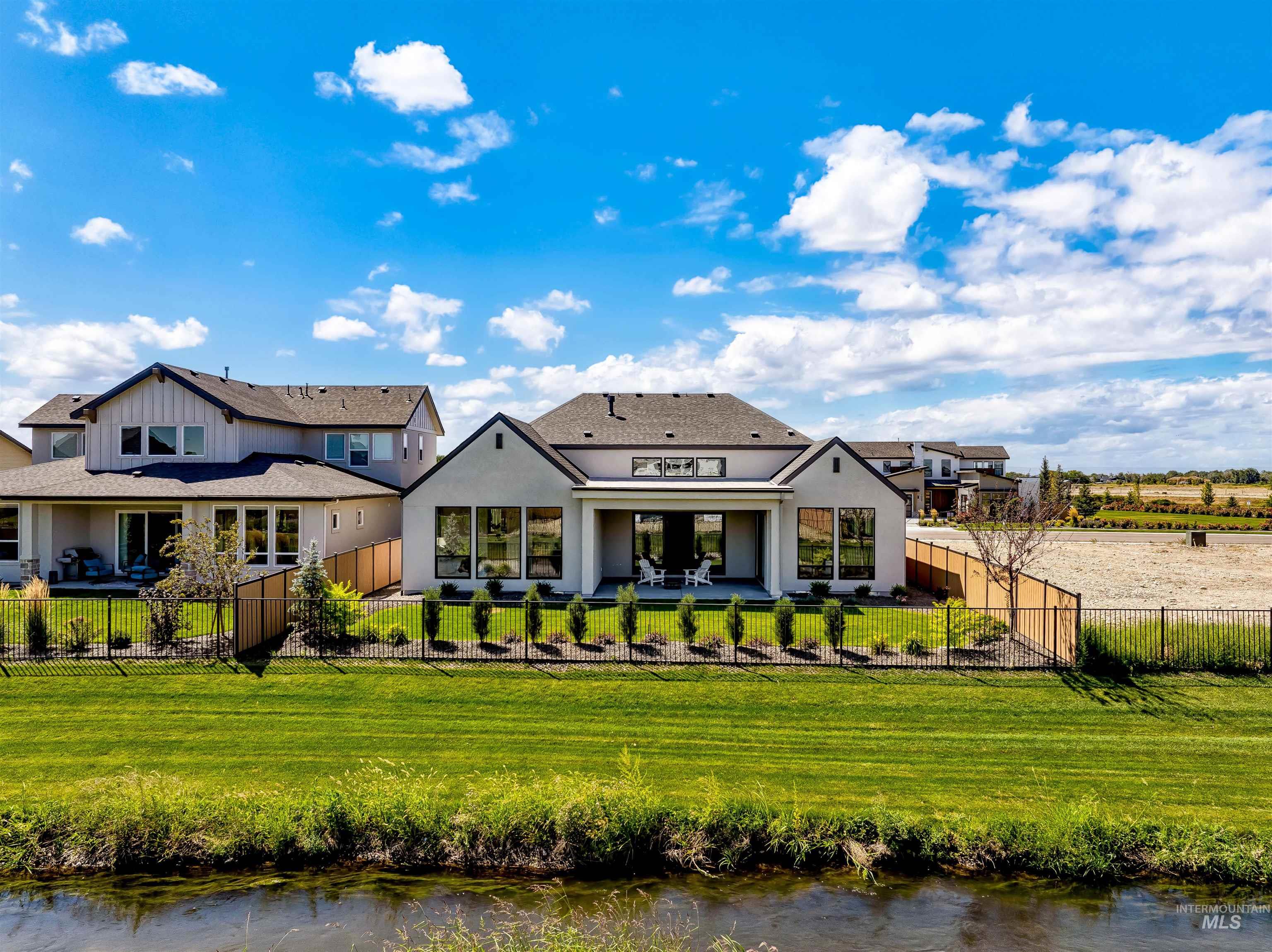 Back of house with a water view, a fenced backyard, a patio, and stucco siding