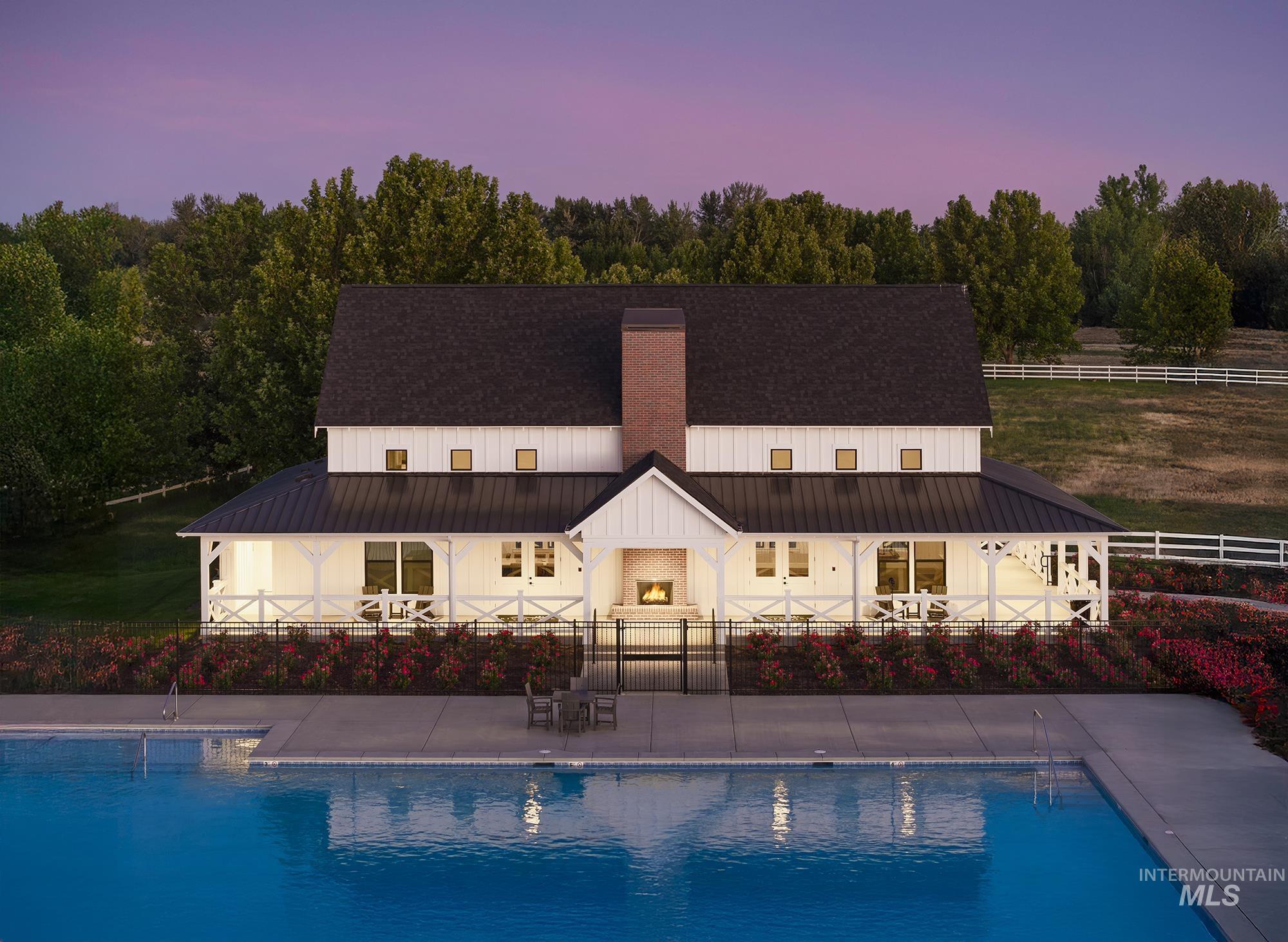 Back of house at dusk with a patio area, a metal roof, an outdoor pool, and a chimney