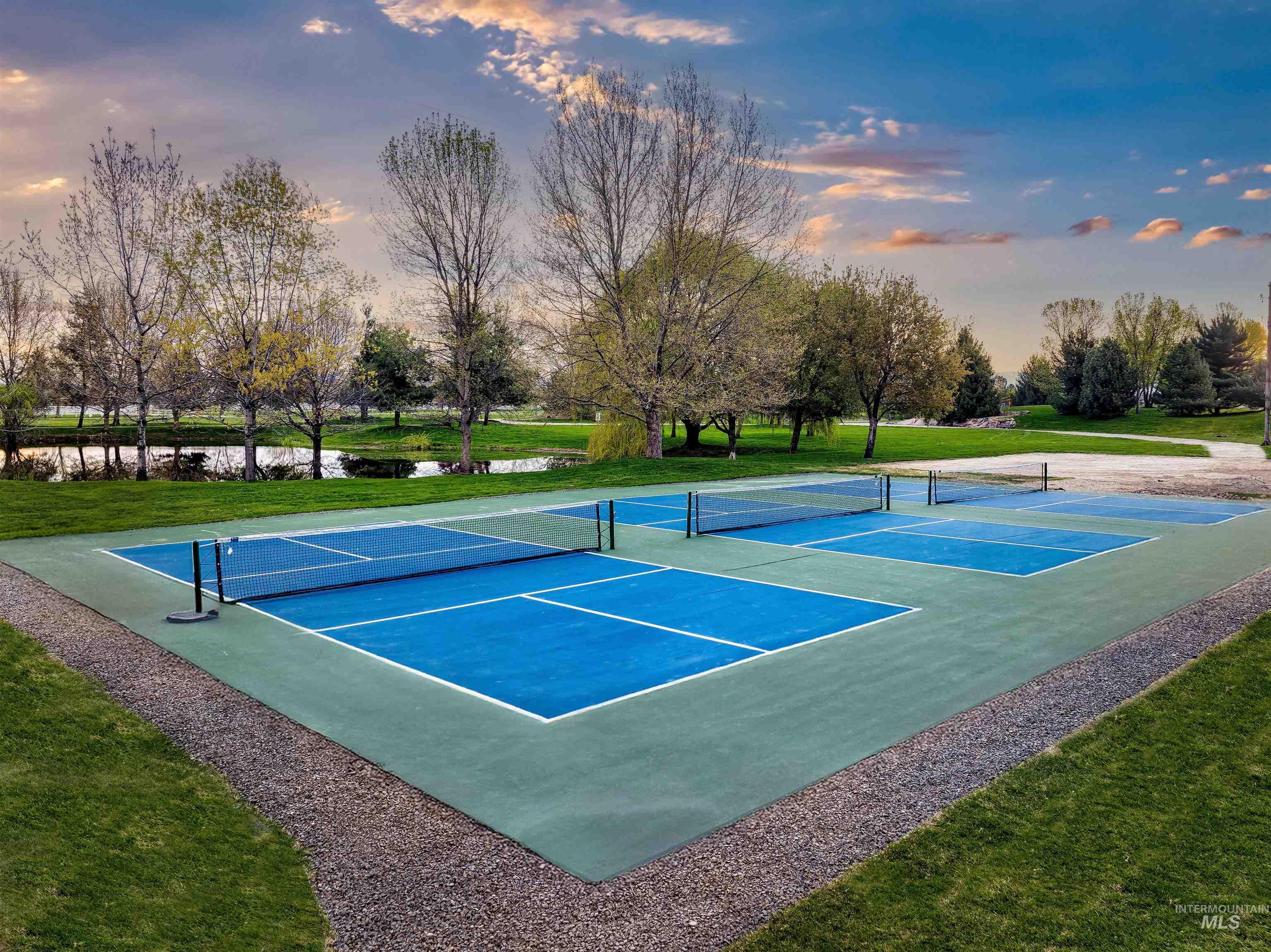 View of tennis court with a yard and community basketball court