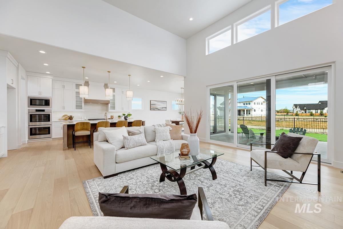 Living room featuring healthy amount of natural light, light wood-style floors, recessed lighting, and a high ceiling