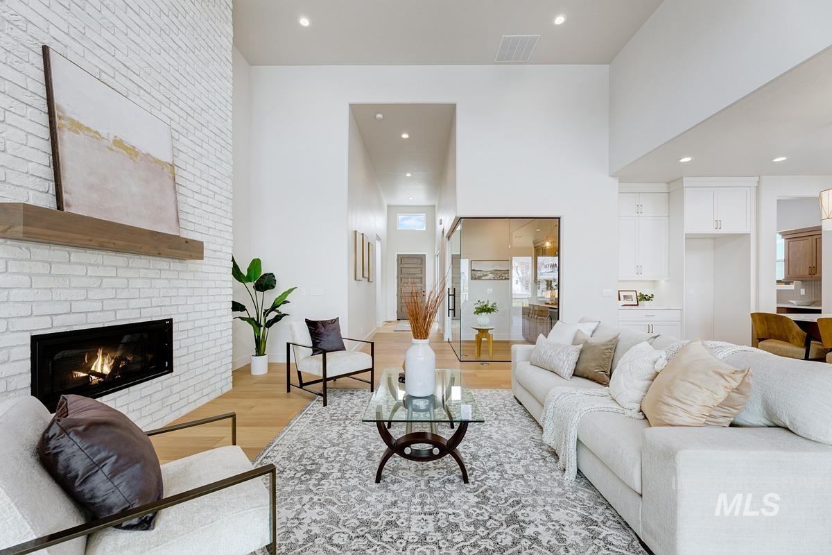 Living room featuring light wood-type flooring, recessed lighting, a towering ceiling, and a fireplace