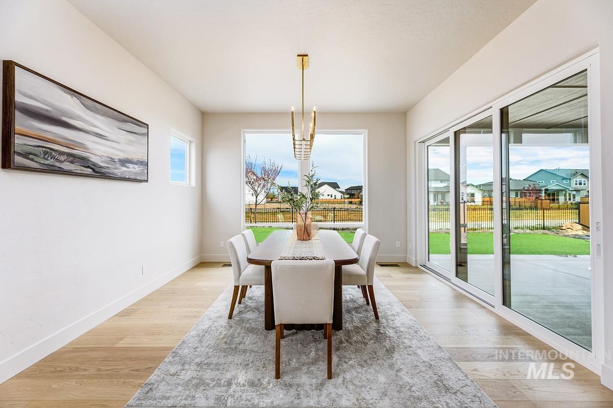 Dining area with a residential view, light wood-style floors, plenty of natural light, and a chandelier