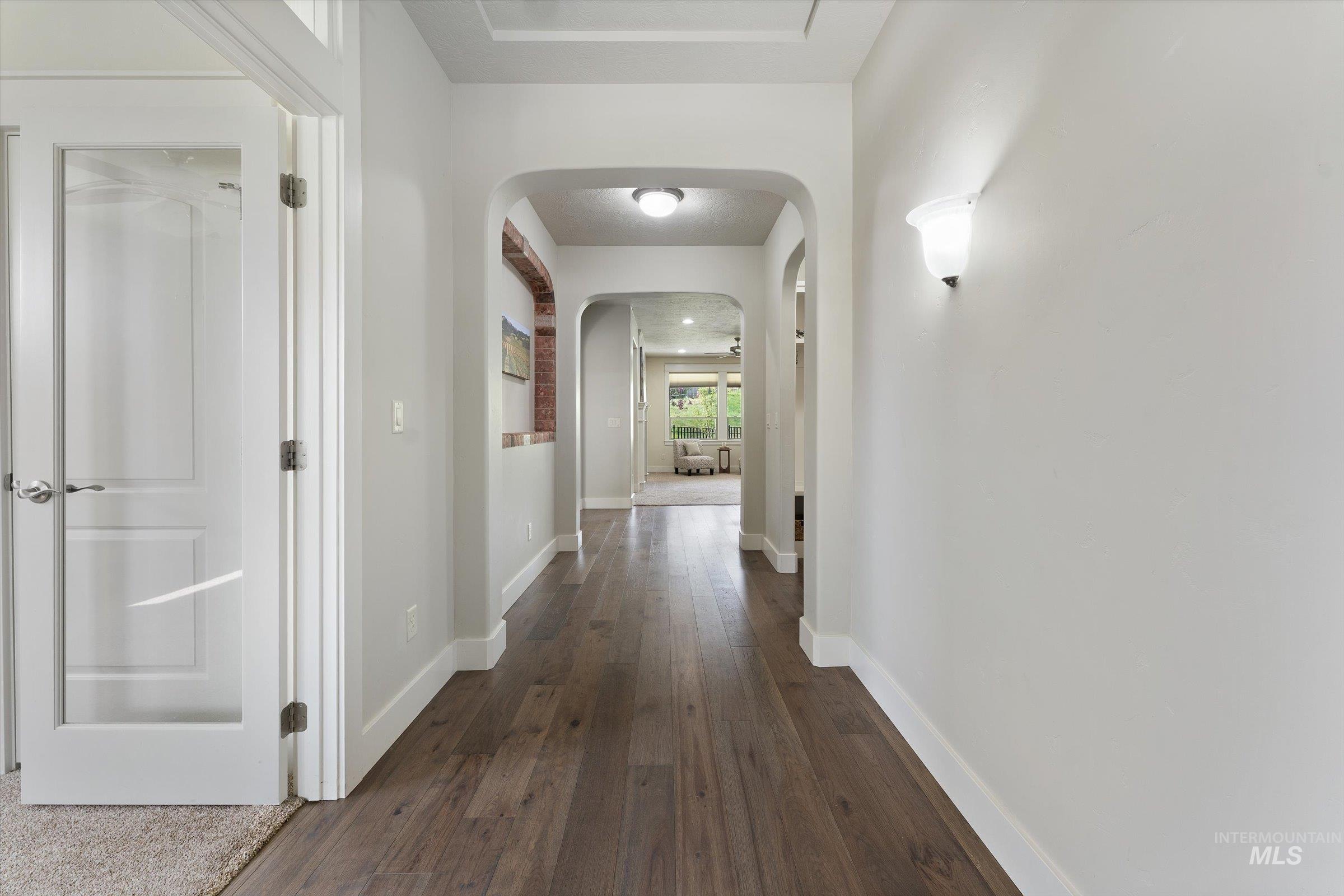 Corridor featuring dark wood-type flooring and arched walkways
