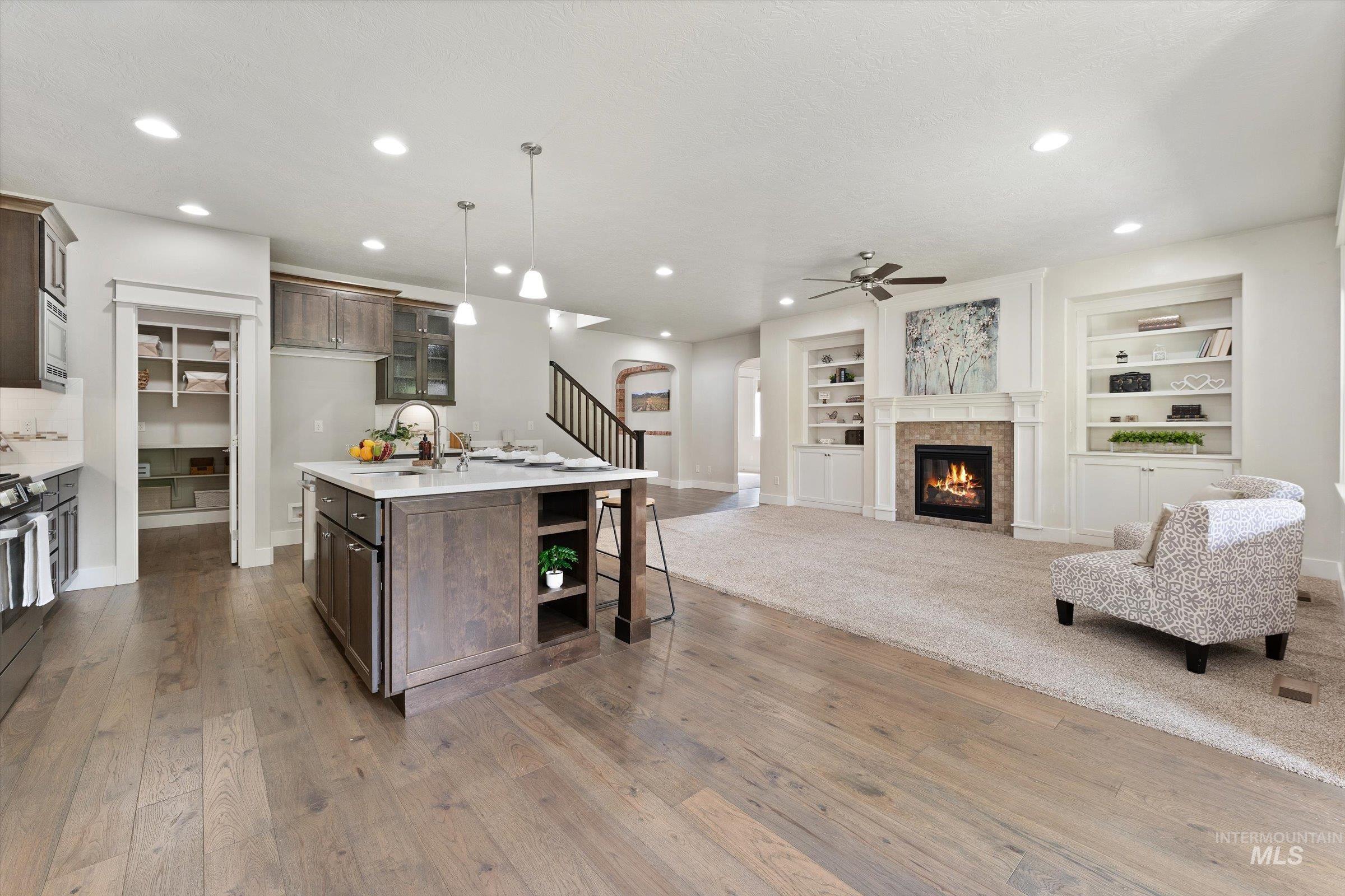 Kitchen with built in features, hanging light fixtures, open floor plan, recessed lighting, and dark brown cabinetry