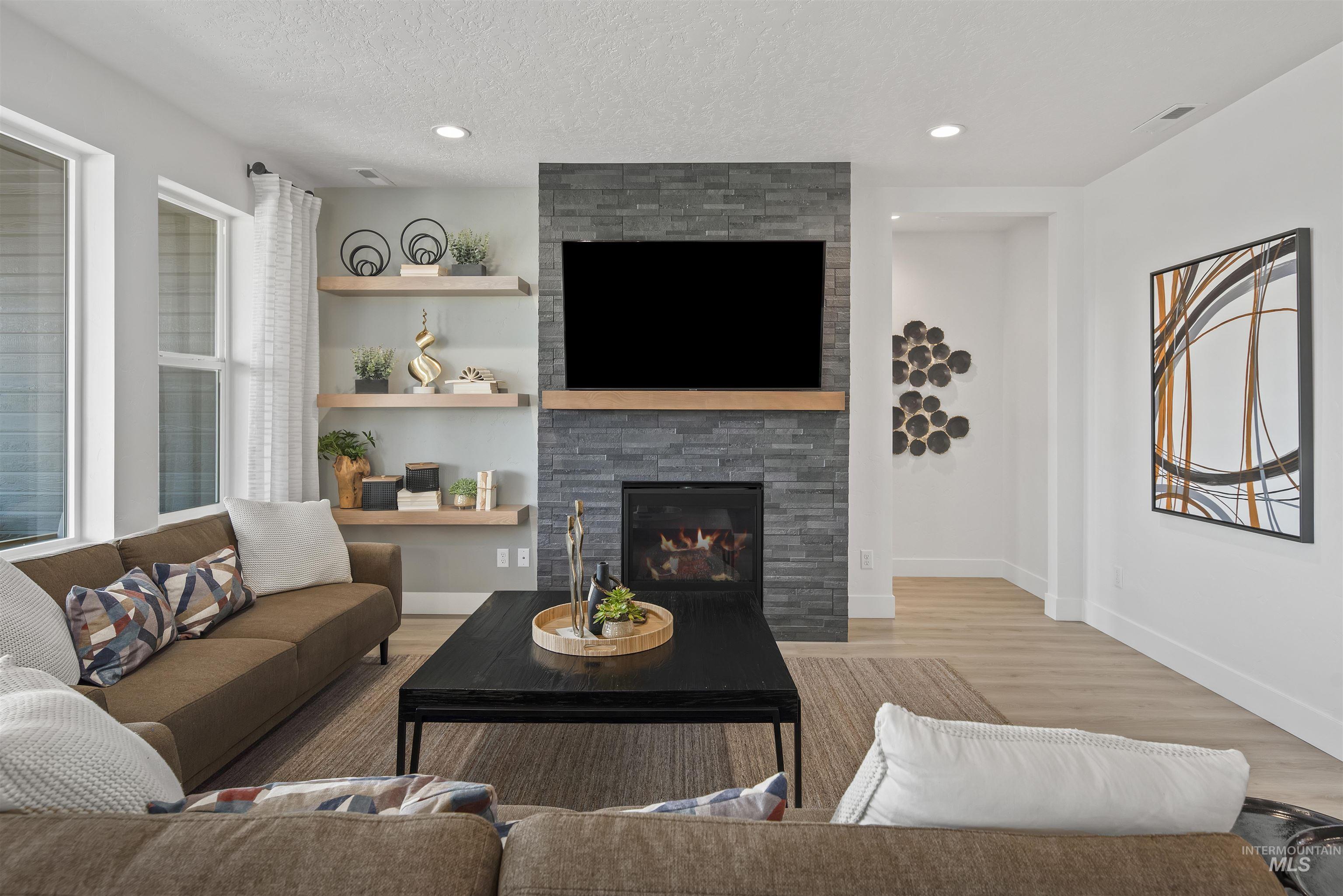 Living room with a textured ceiling, a fireplace, light wood-style floors, and recessed lighting