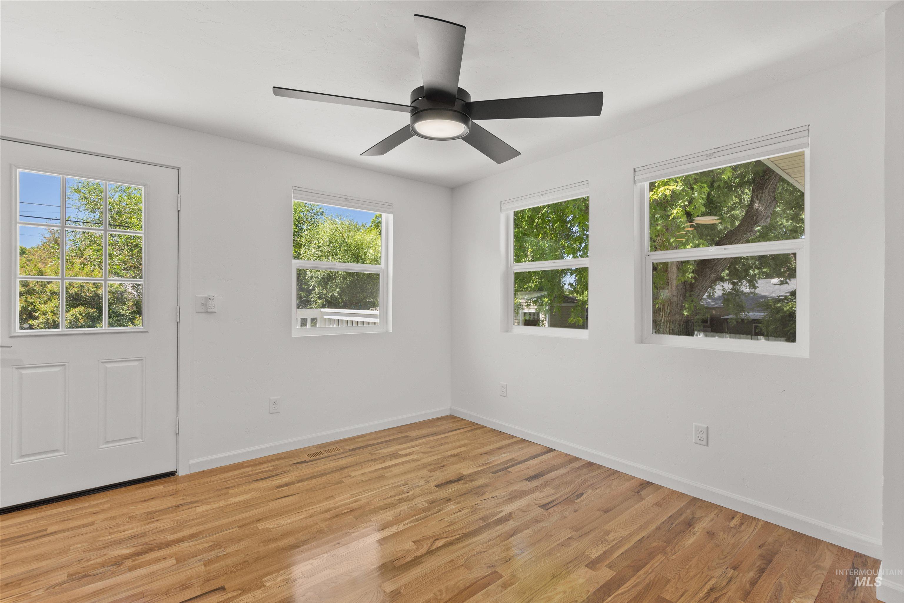 Empty room with light wood-style floors and a ceiling fan