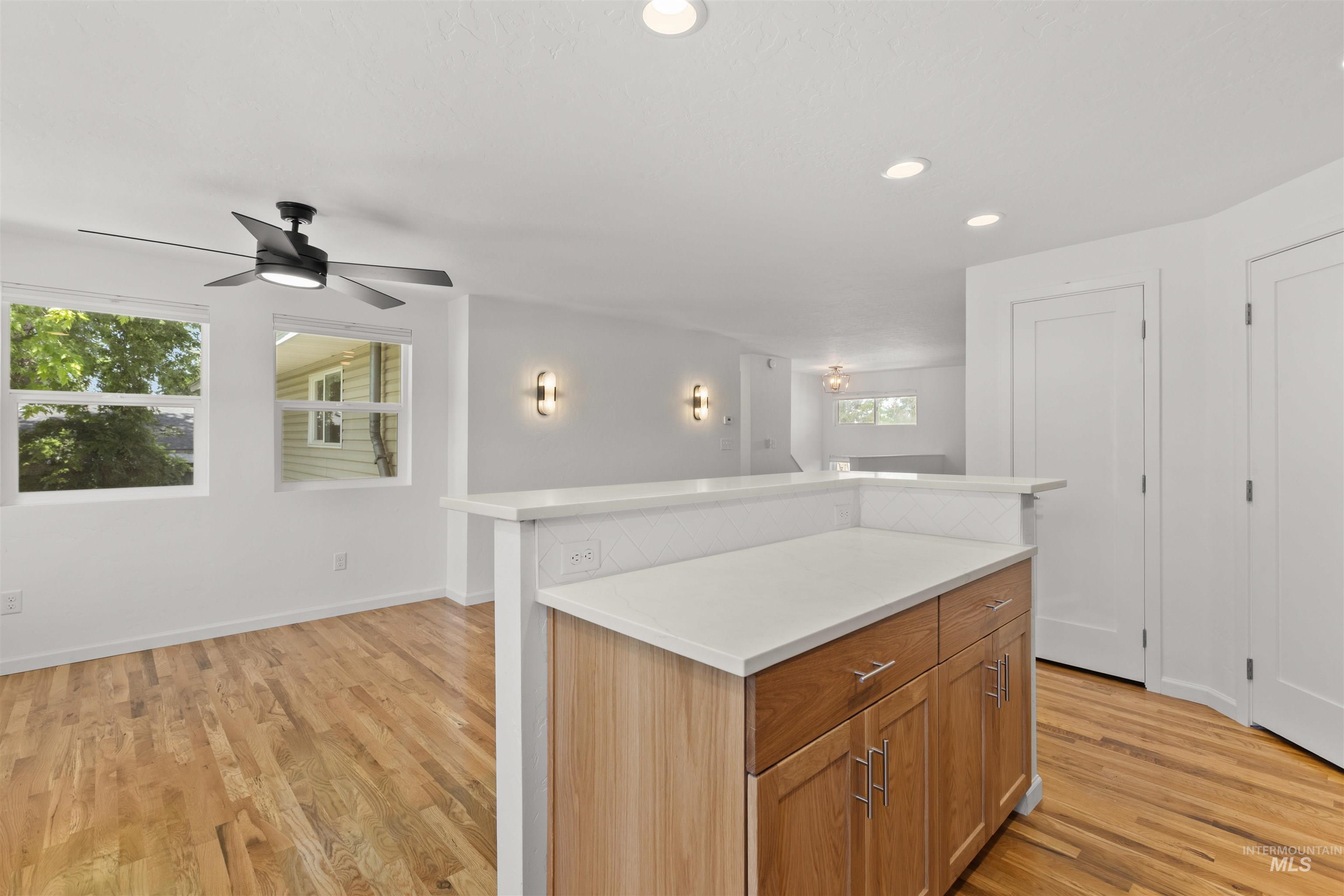 Kitchen with light countertops, light wood-style floors, a center island, a ceiling fan, and recessed lighting