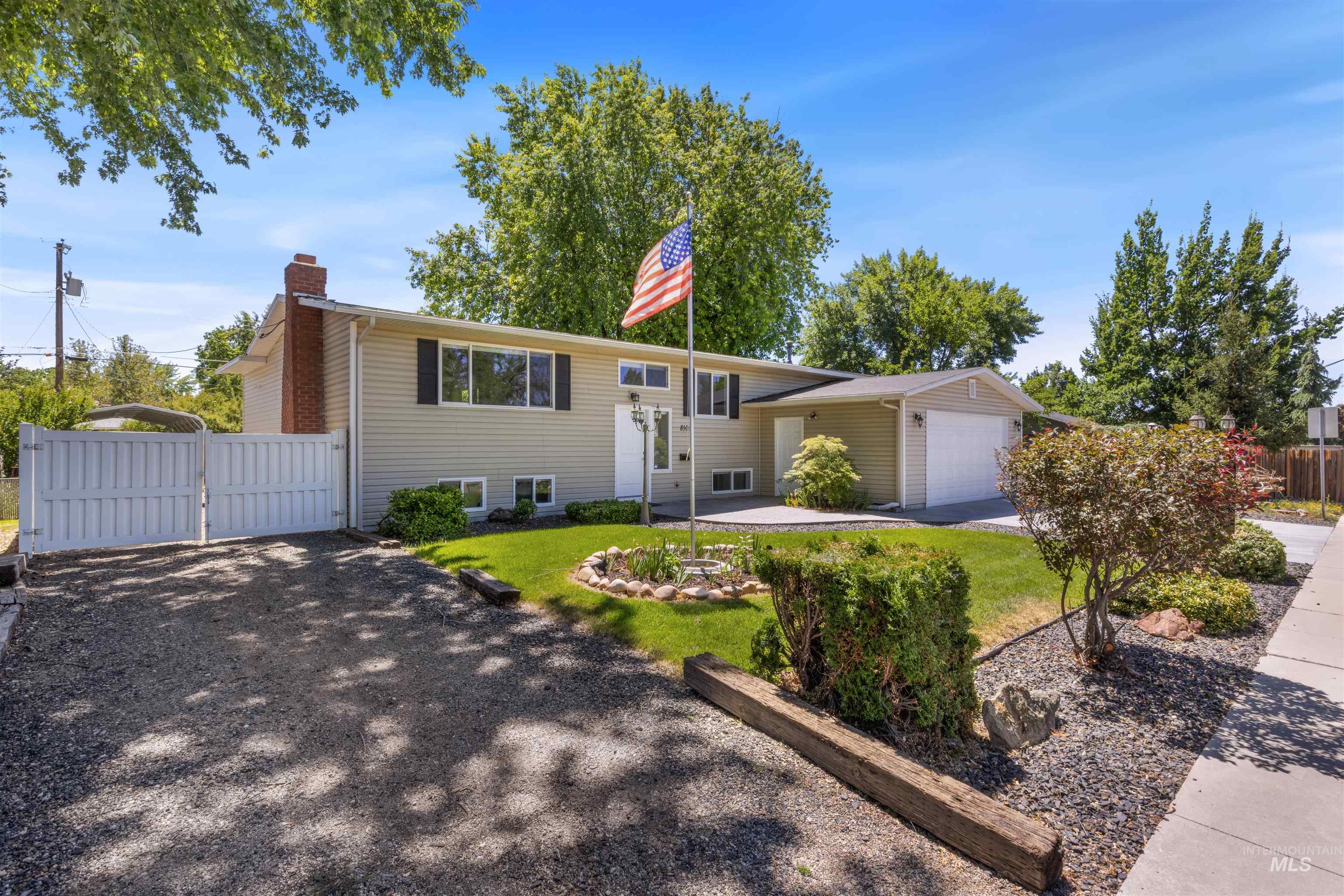Split foyer home with a gate, a chimney, driveway, and an attached garage