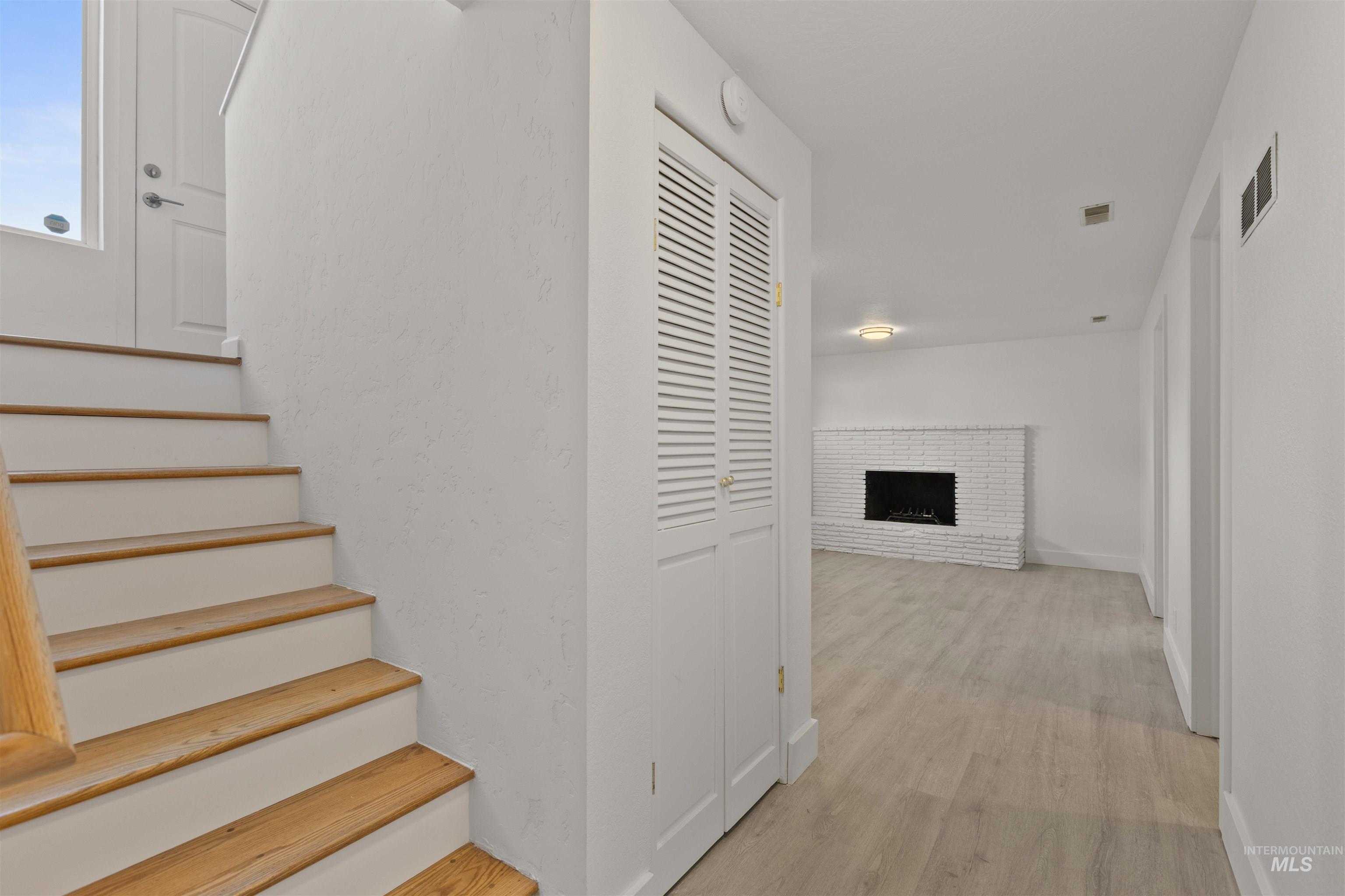 Stairs with wood finished floors and a fireplace