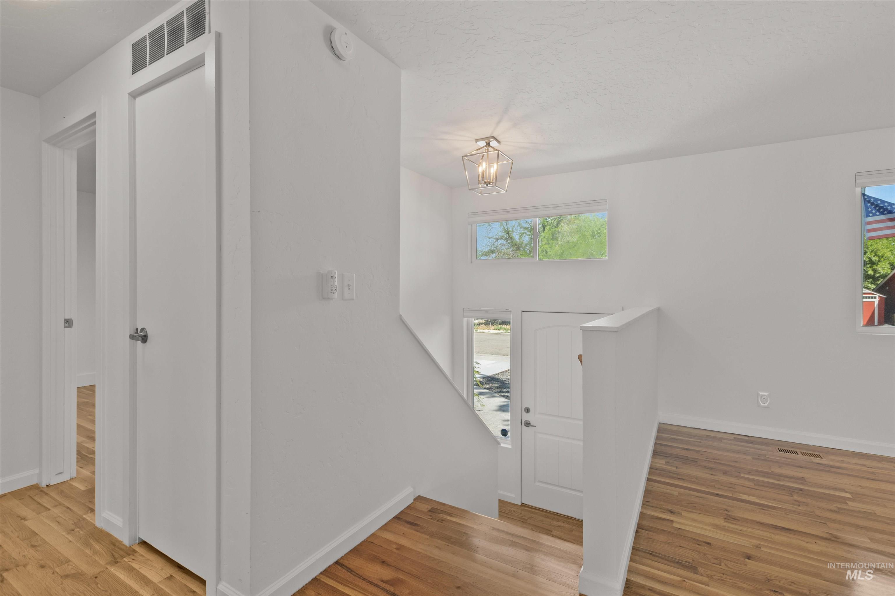 Foyer entrance with wood finished floors and a chandelier