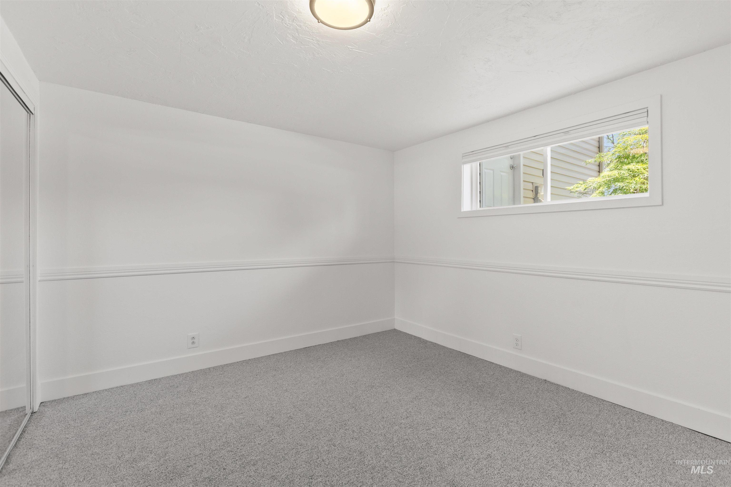 Carpeted spare room featuring baseboards