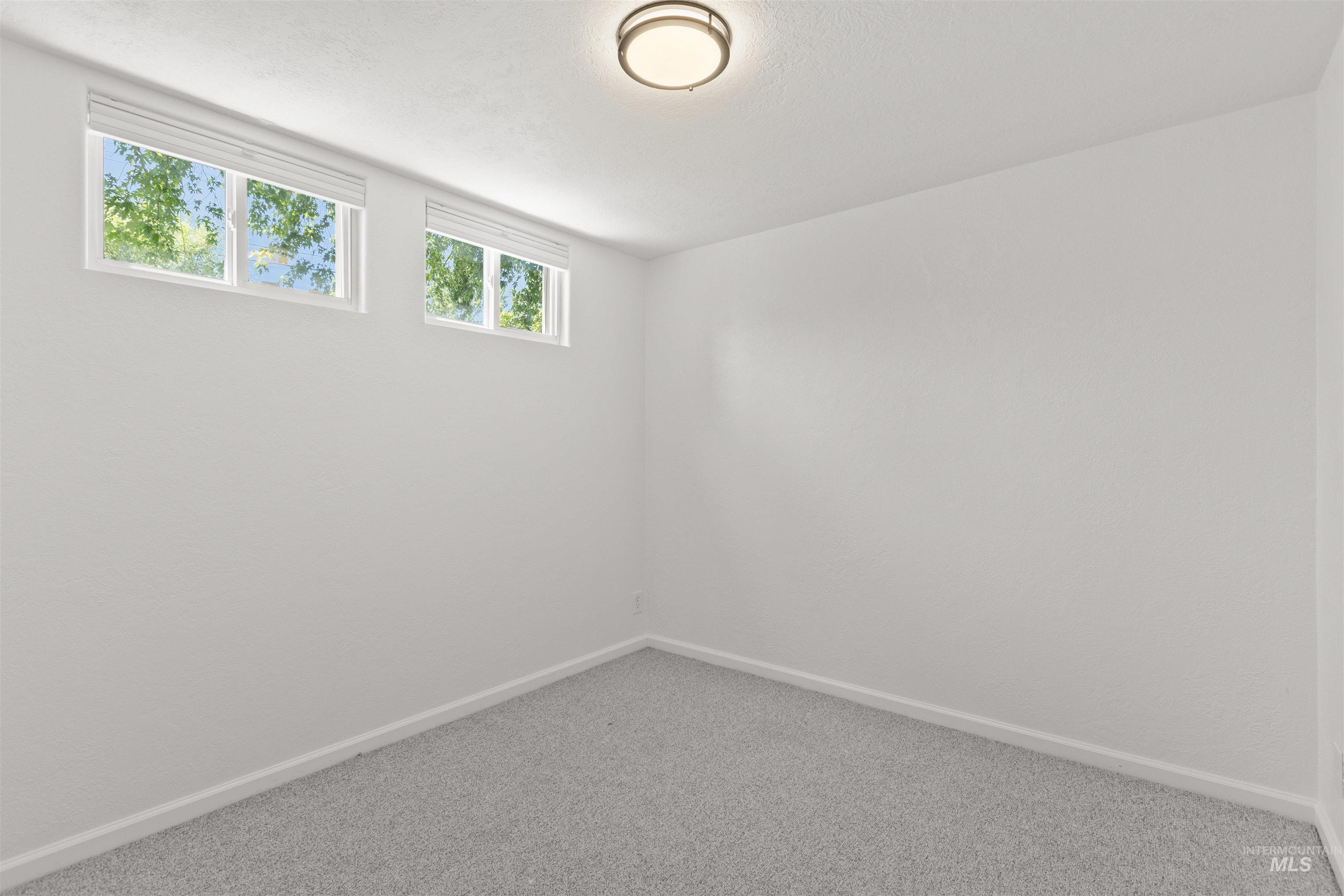 Carpeted spare room featuring baseboards