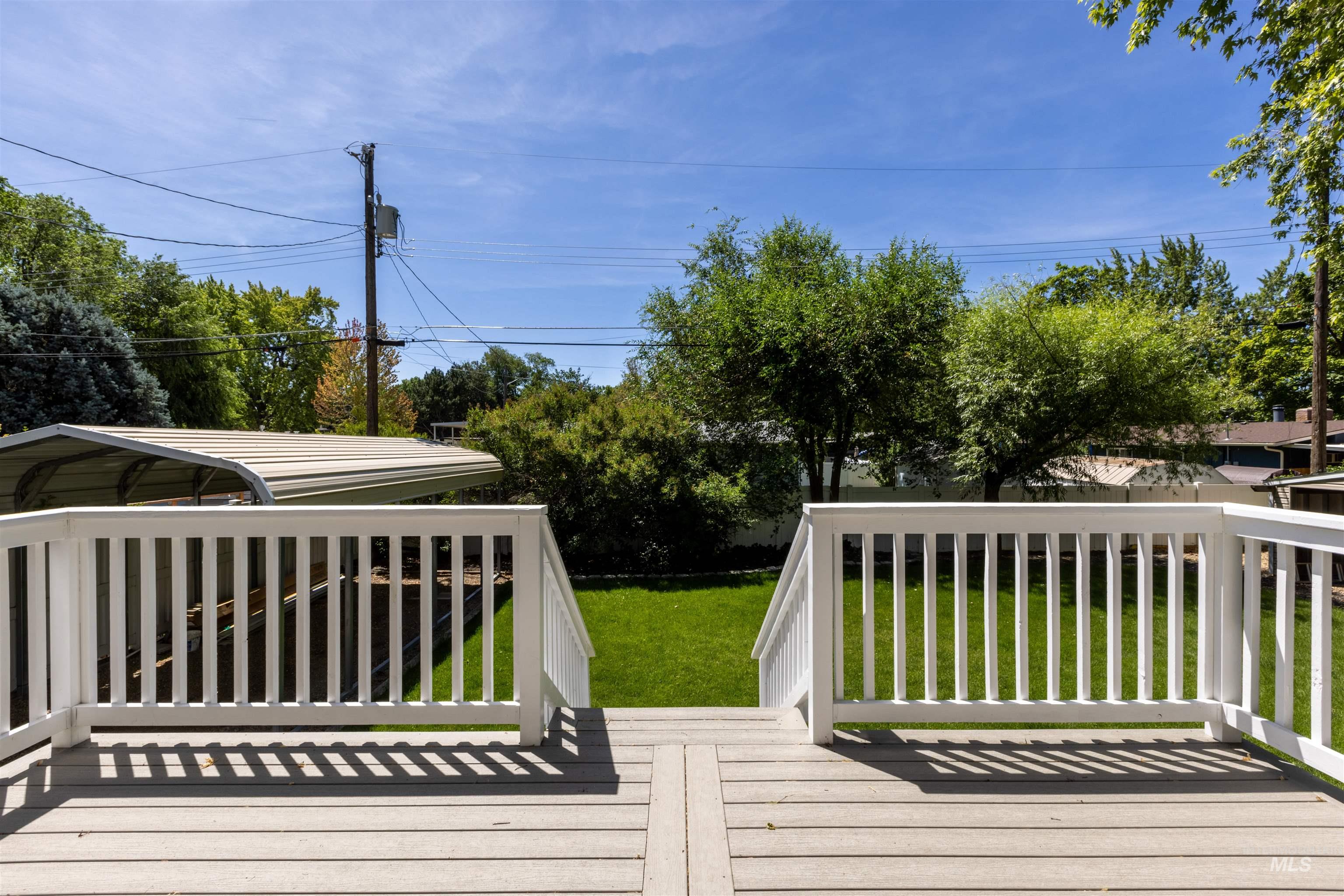 Wooden deck featuring a yard and a carport