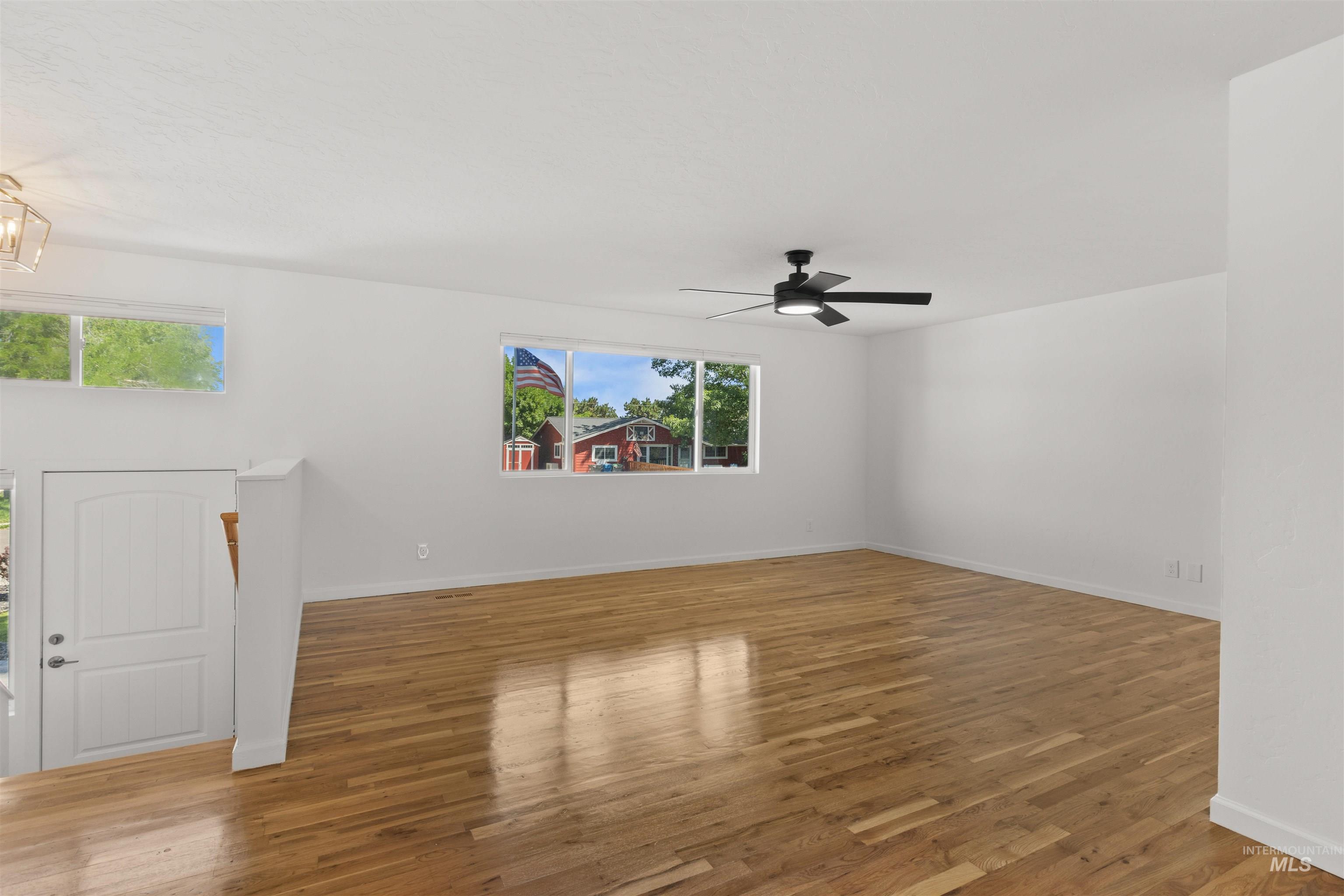 Spare room featuring plenty of natural light, wood finished floors, and a ceiling fan