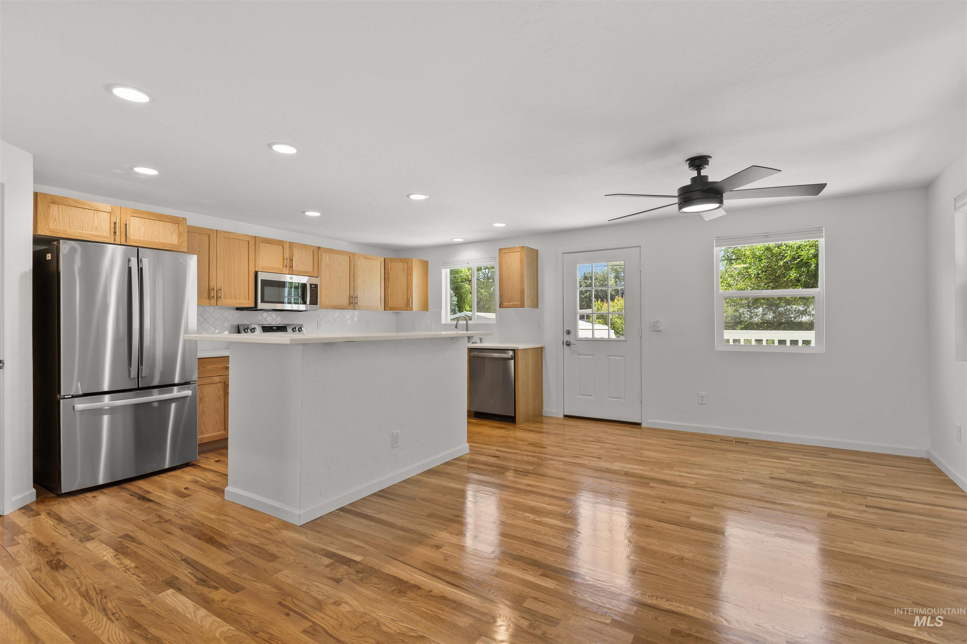 Kitchen with appliances with stainless steel finishes, light countertops, recessed lighting, light wood-style flooring, and ceiling fan