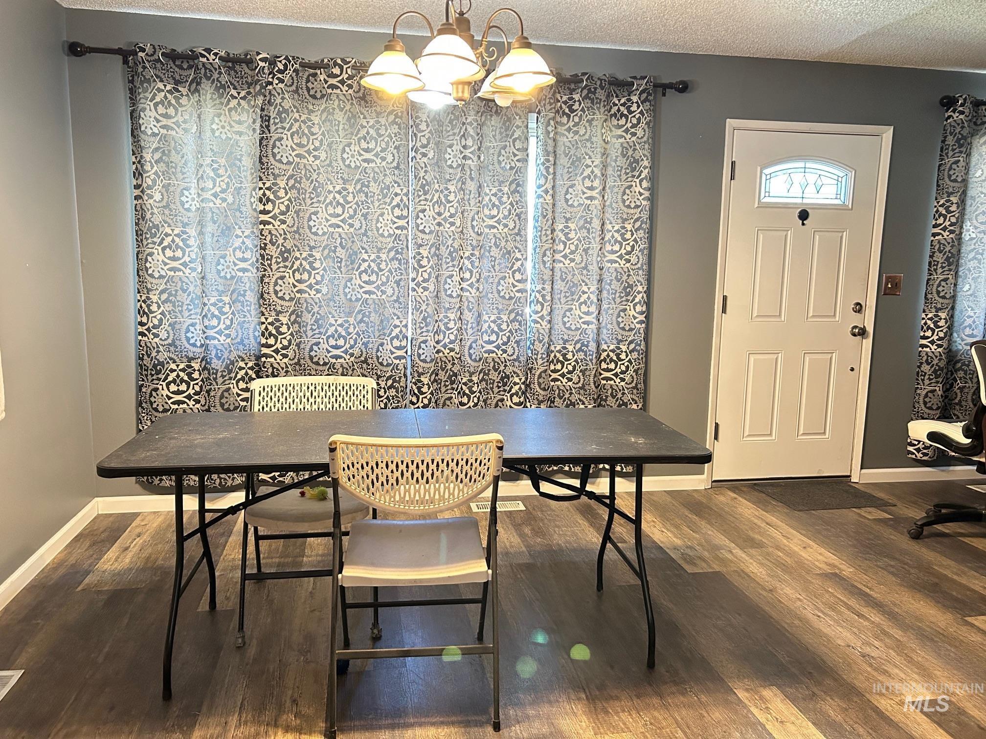 Dining space featuring a textured ceiling, wood finished floors, and a chandelier