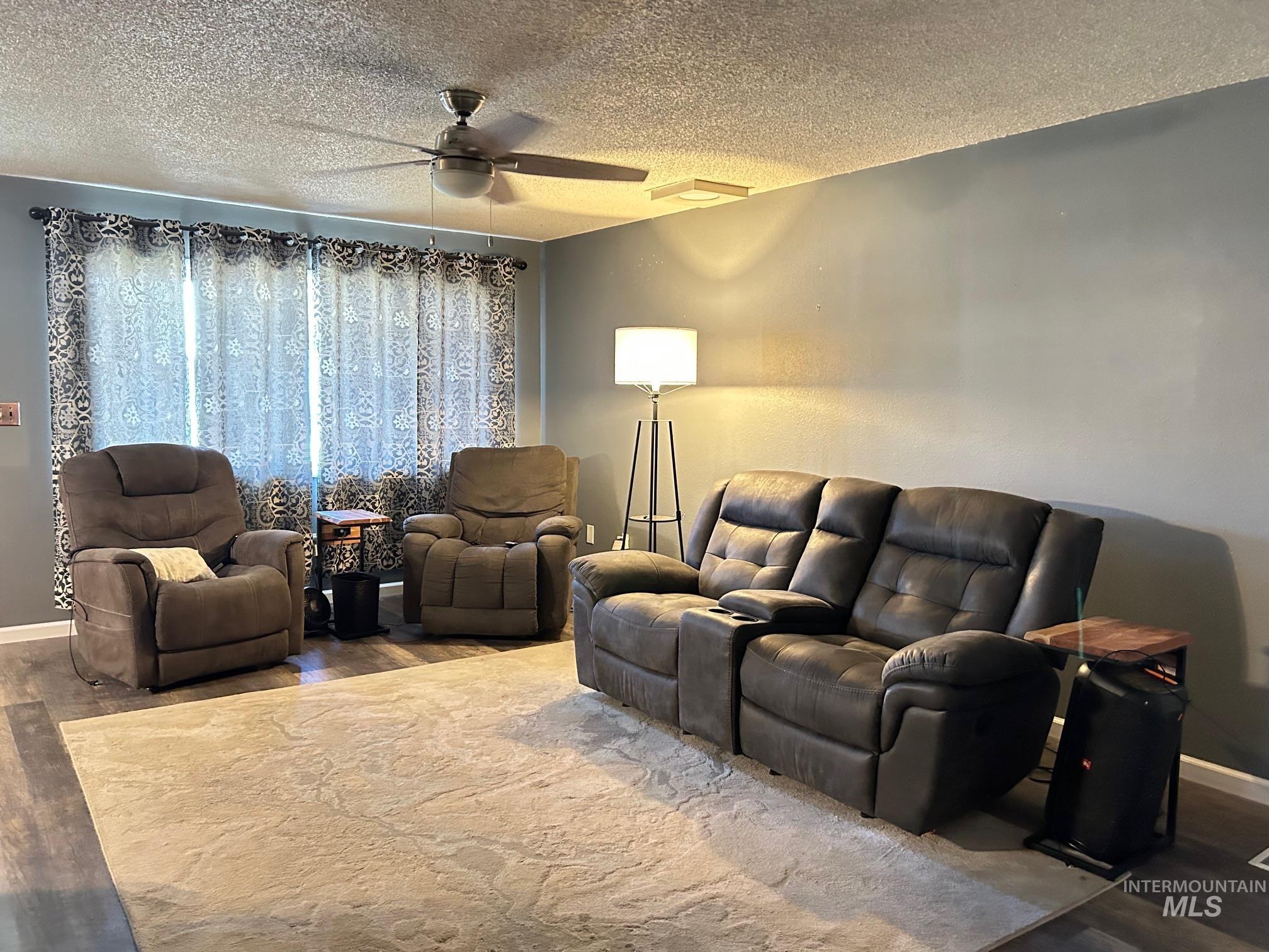 Living area featuring wood finished floors, a ceiling fan, and a textured ceiling