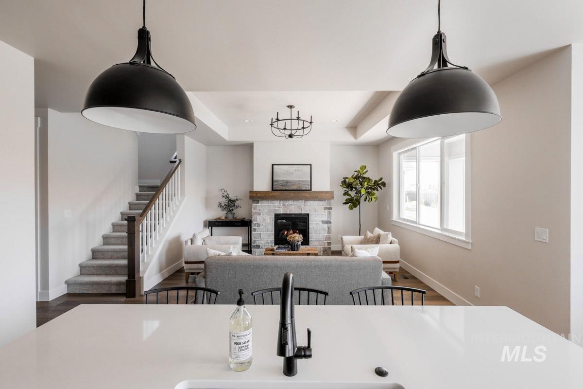 Dining room featuring wood finished floors, a stone fireplace, stairs, a tray ceiling, and recessed lighting