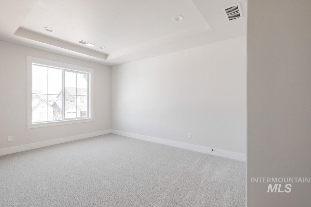 Unfurnished room featuring light carpet, a tray ceiling, and recessed lighting