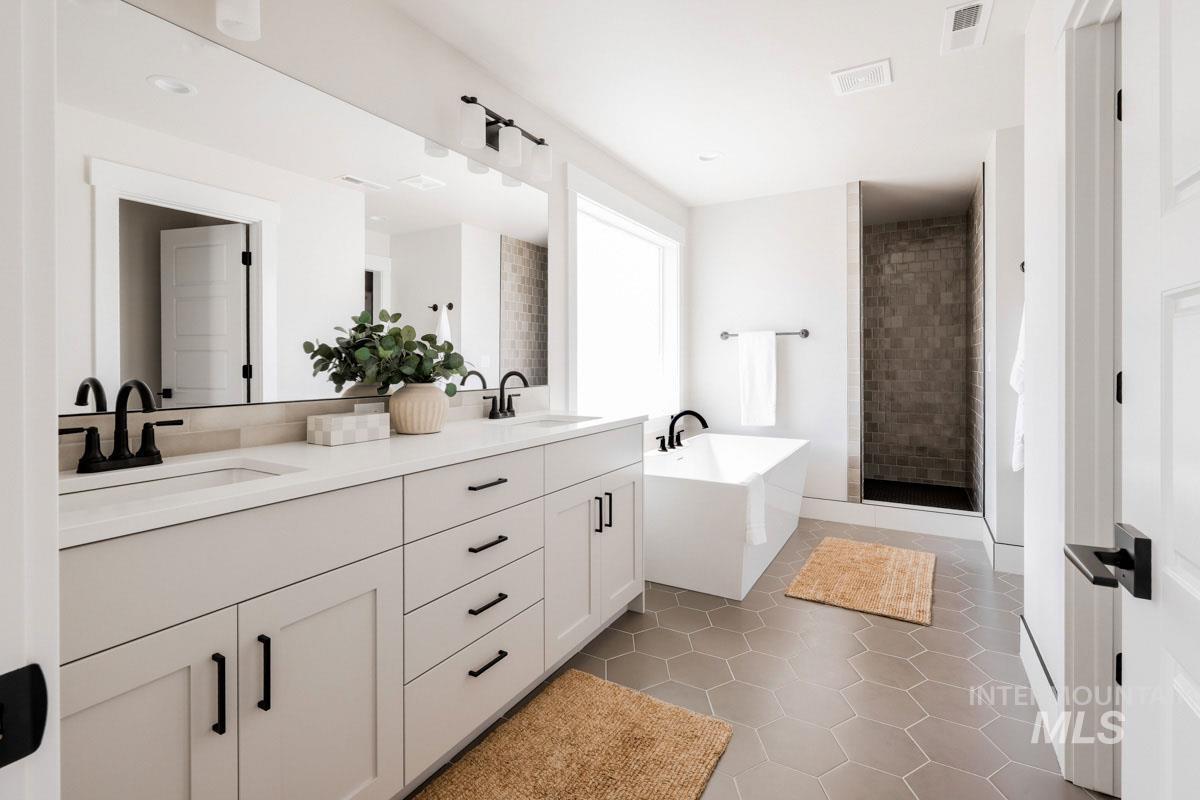 Full bathroom with a soaking tub, double vanity, tile patterned floors, and a shower stall