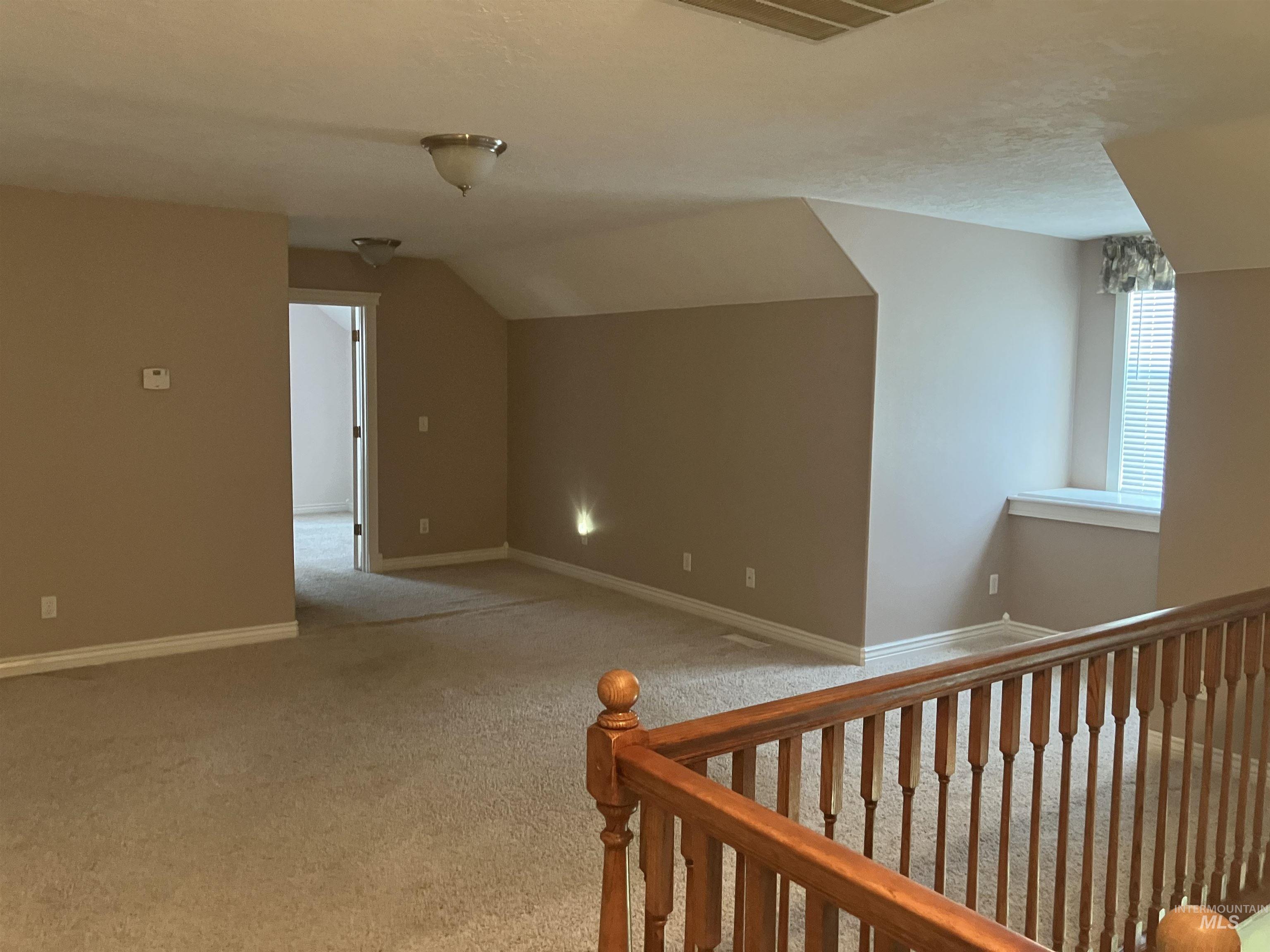Bonus room featuring light colored carpet and vaulted ceiling