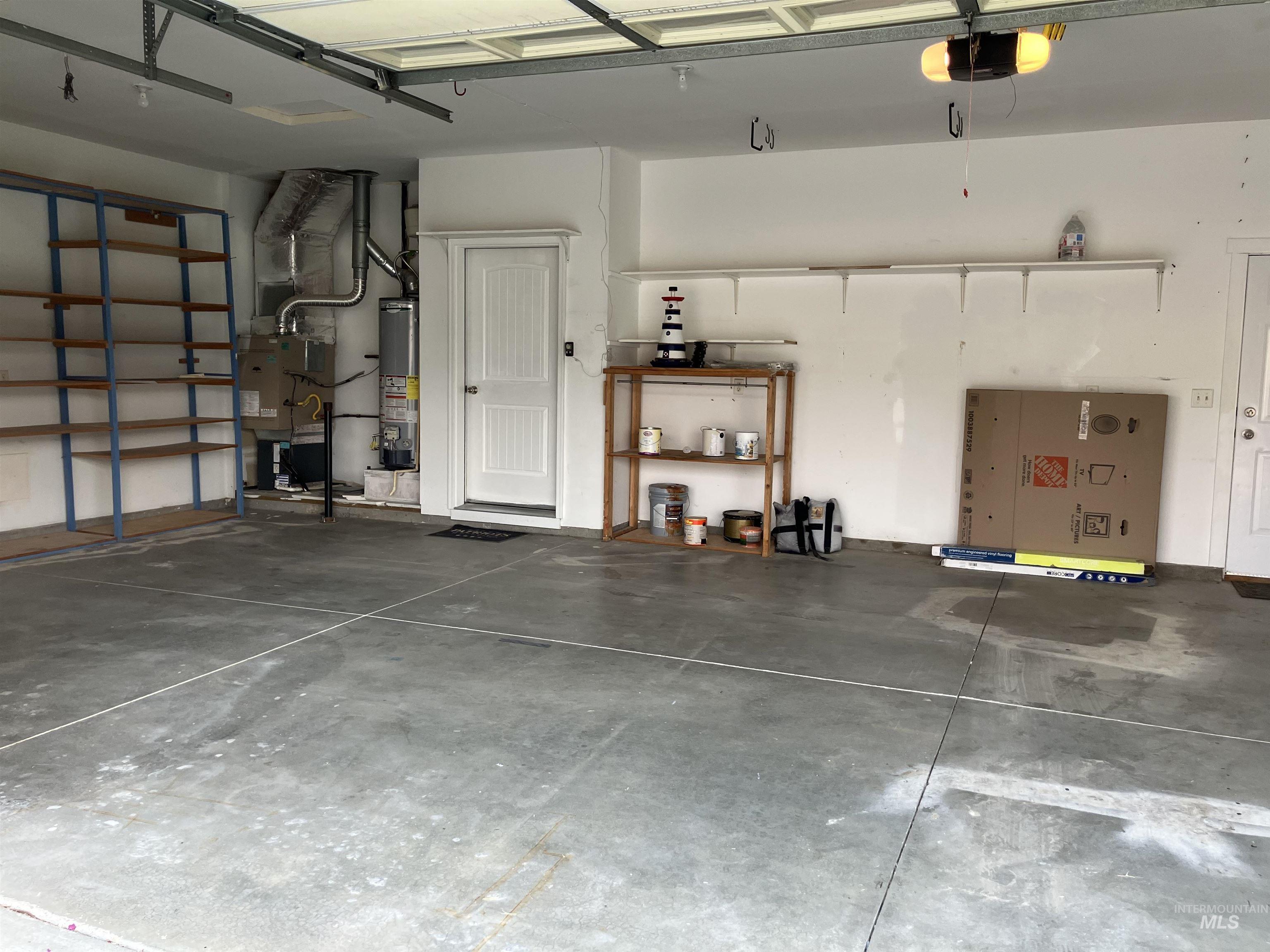 Garage featuring heating unit, gas water heater, and a garage door opener