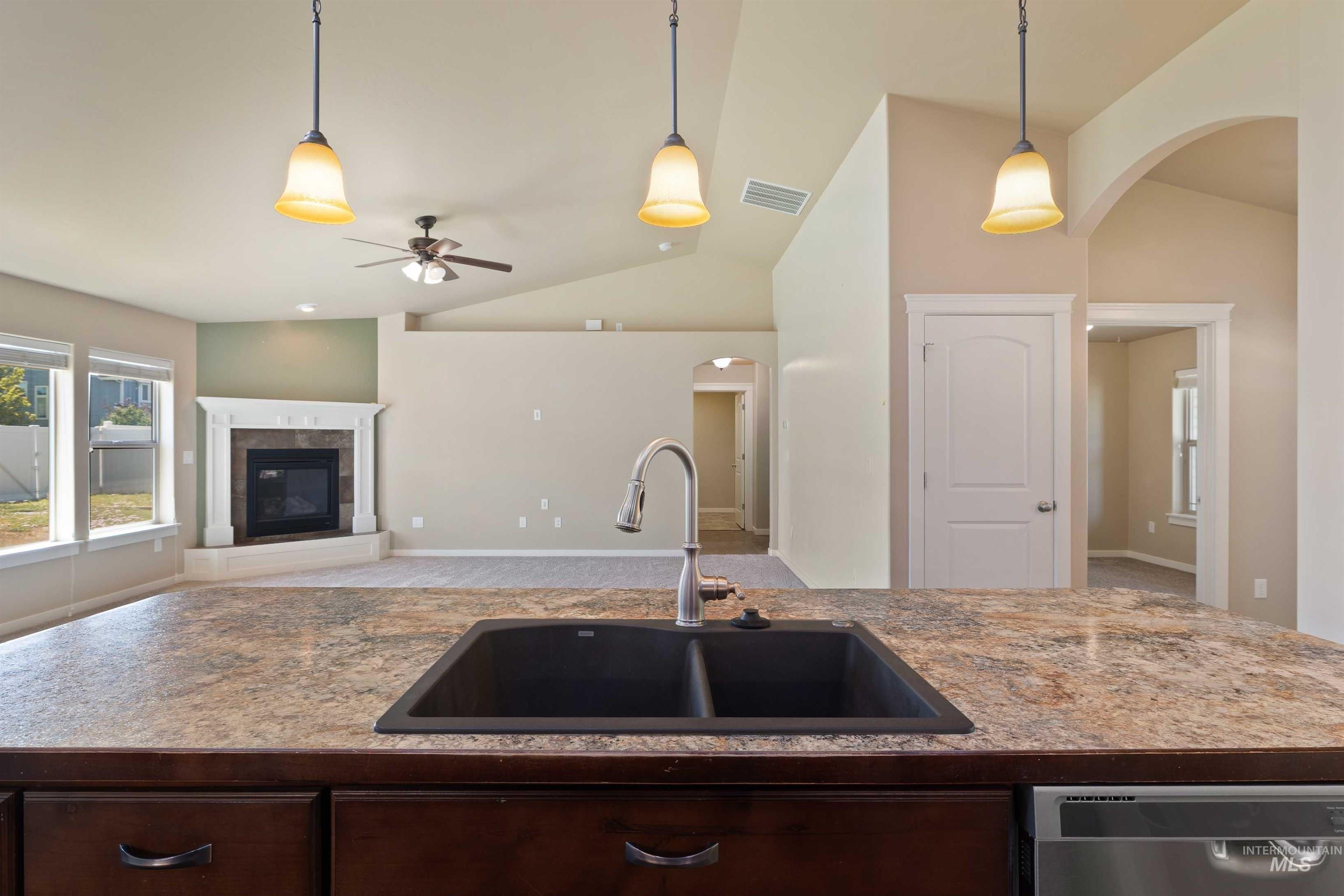 Kitchen featuring dishwasher, vaulted ceiling, dark brown cabinetry, a ceiling fan, and pendant lighting